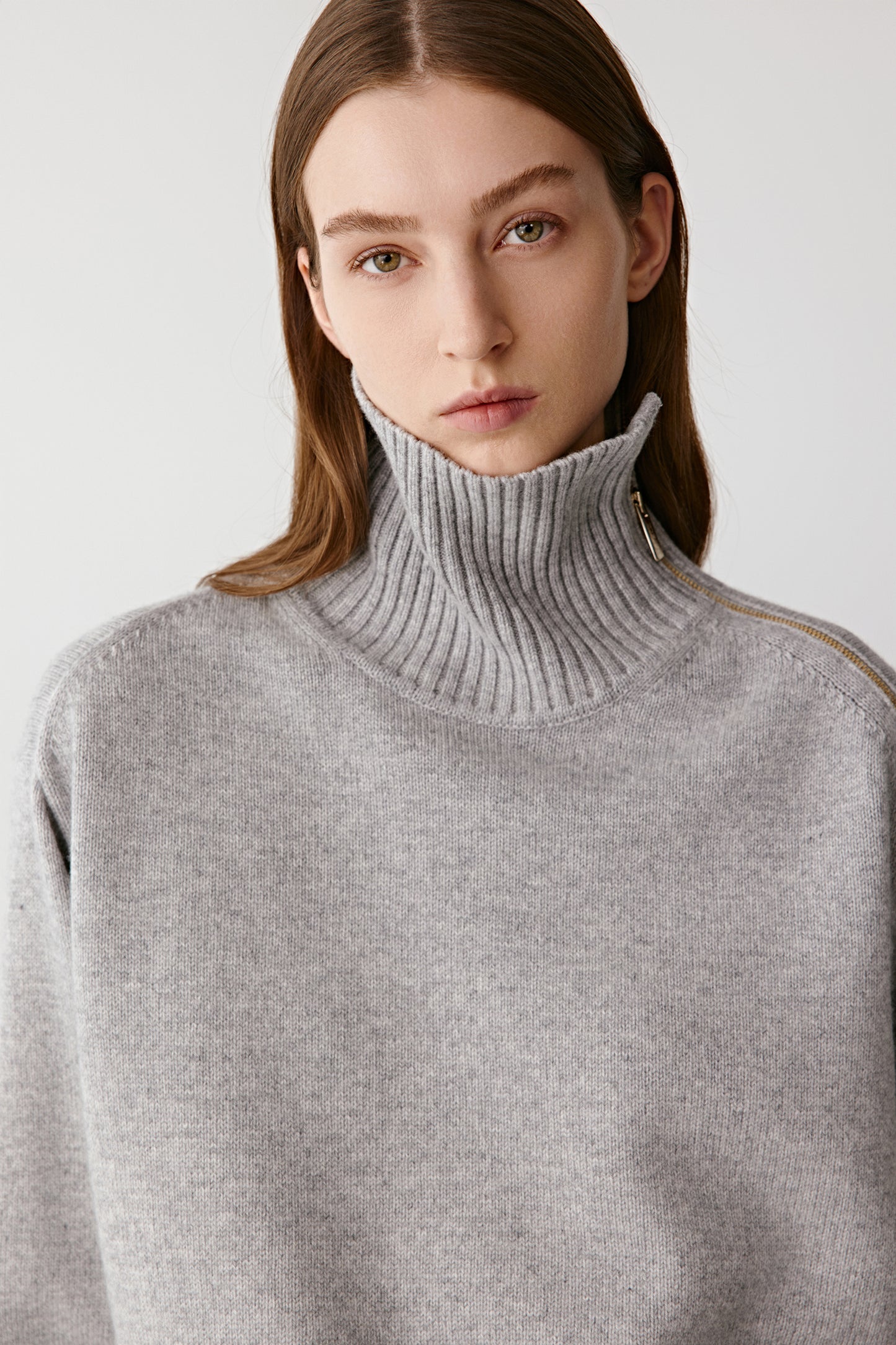 Portrait view highlighting the funnel neck with a subtle zip at the shoulder and soft texture of the knit.