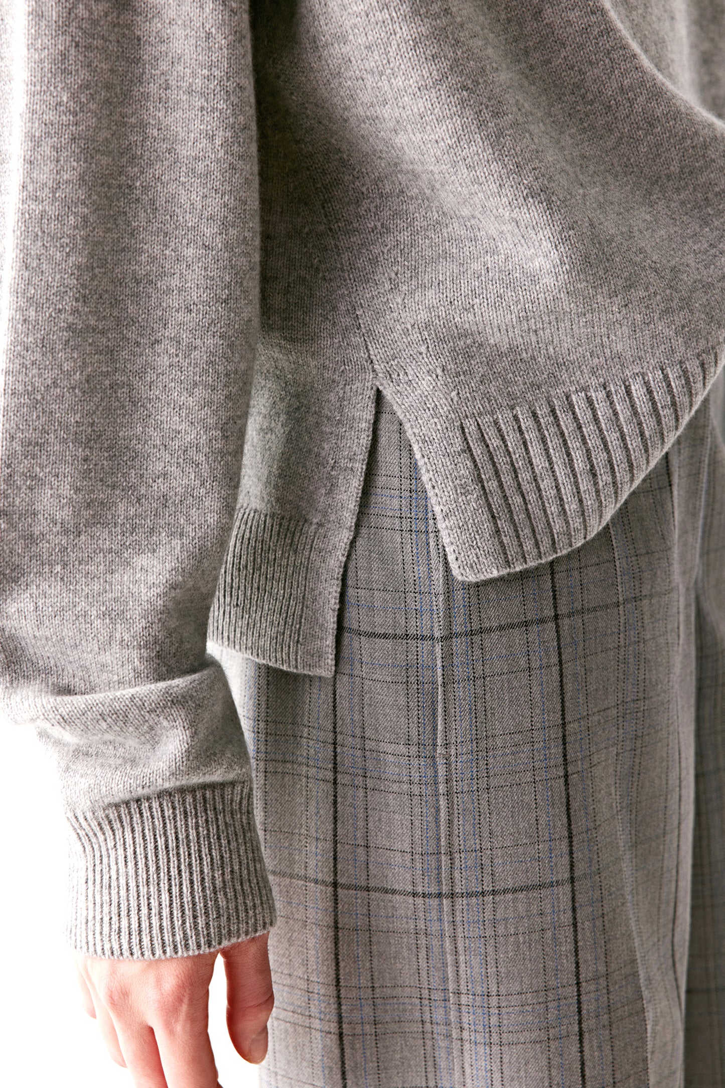 Three-quarter back view capturing the layered hem and relaxed drape of the jumper.