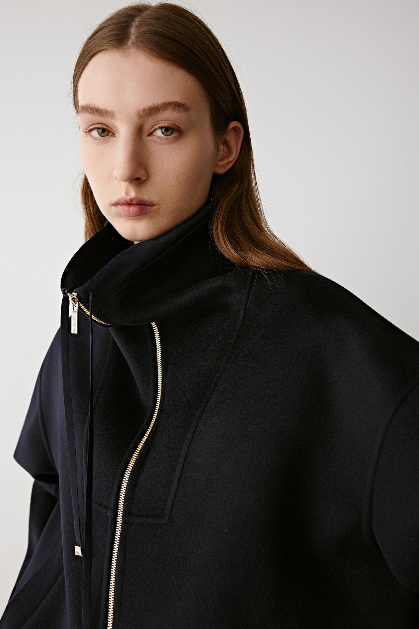 Close-up of the zip fastening and refined stitching details on the black jacket.