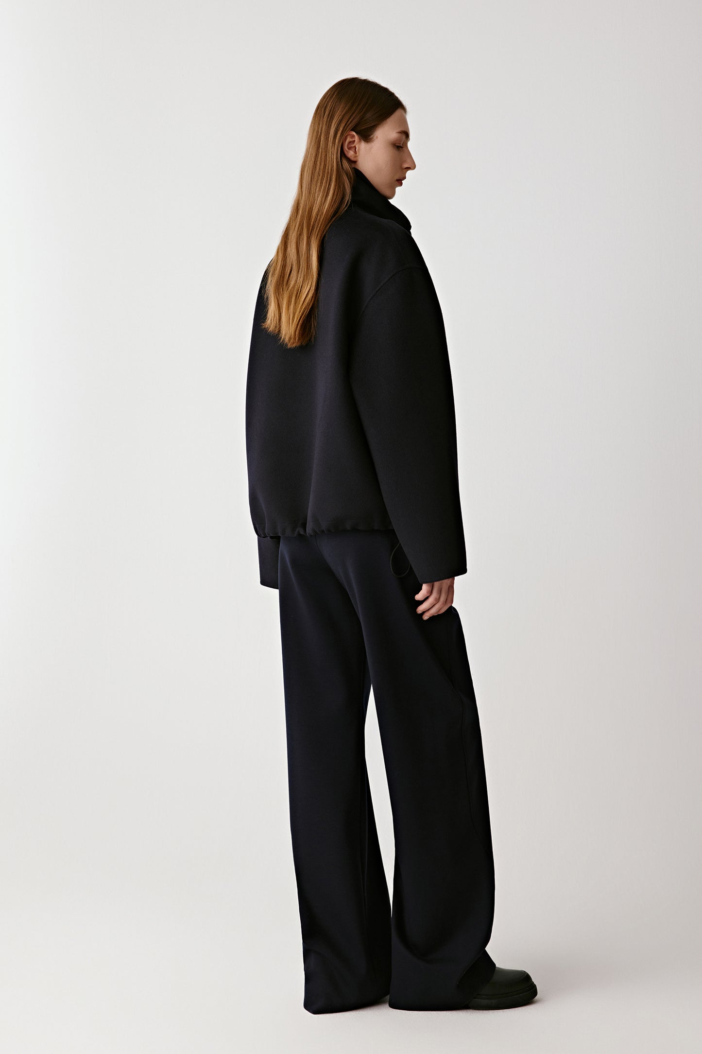 Back view showing the clean, structured silhouette and soft drape of the black wool and silk fabric.