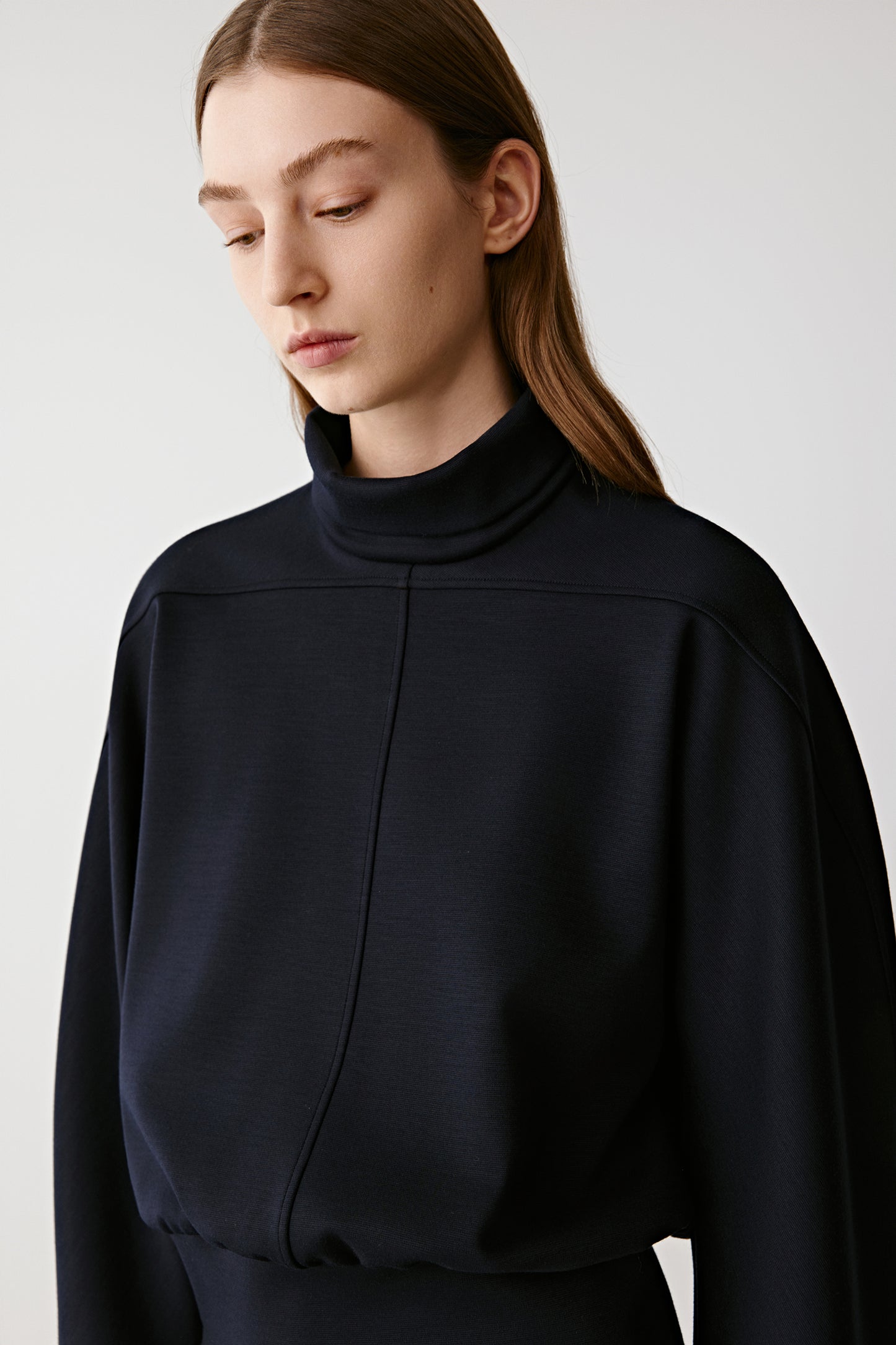 Woman wearing a black turtleneck sweater against a plain background