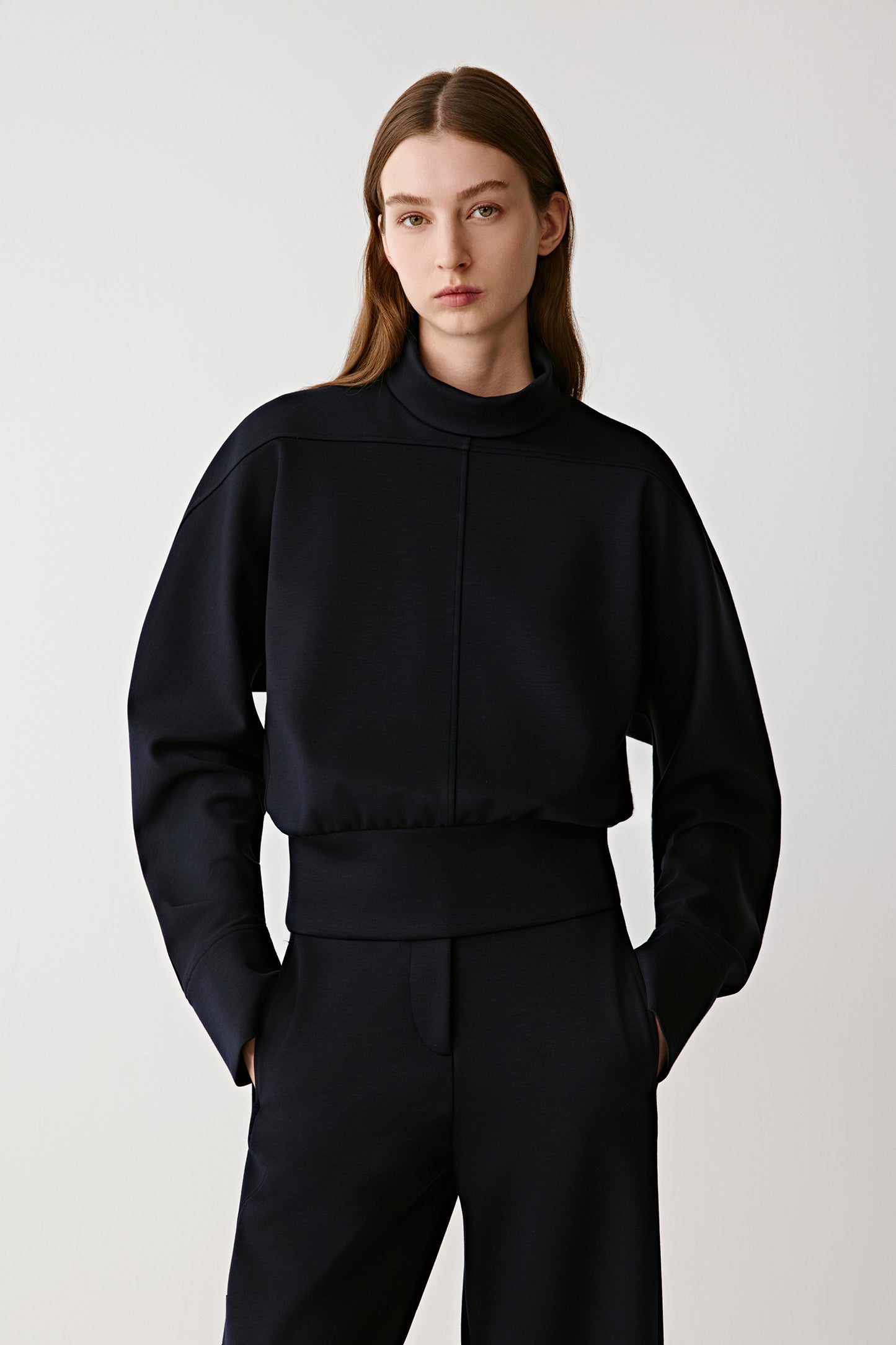 Person wearing a black outfit on a plain background