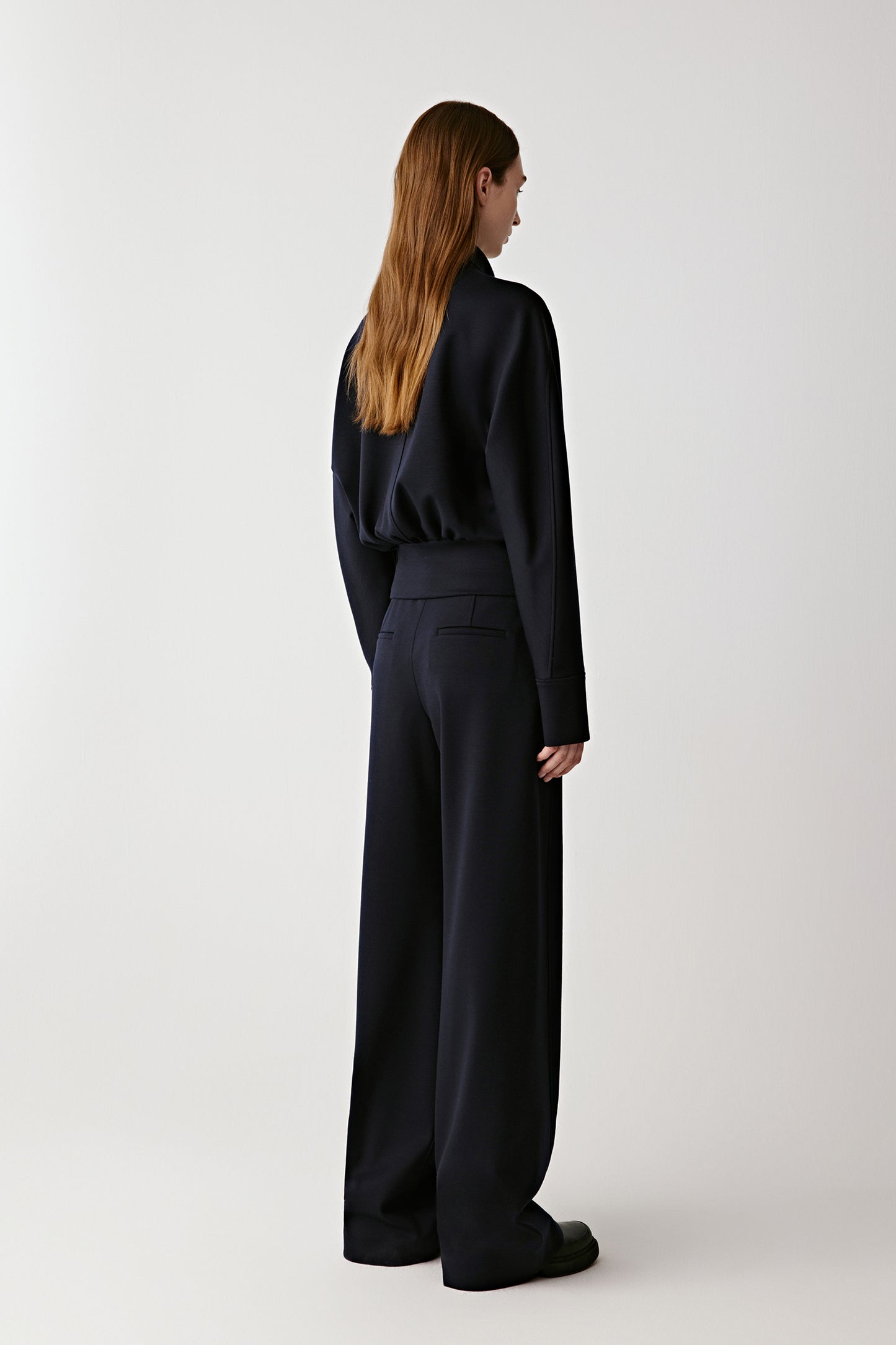 Person wearing a dark outfit on a white background