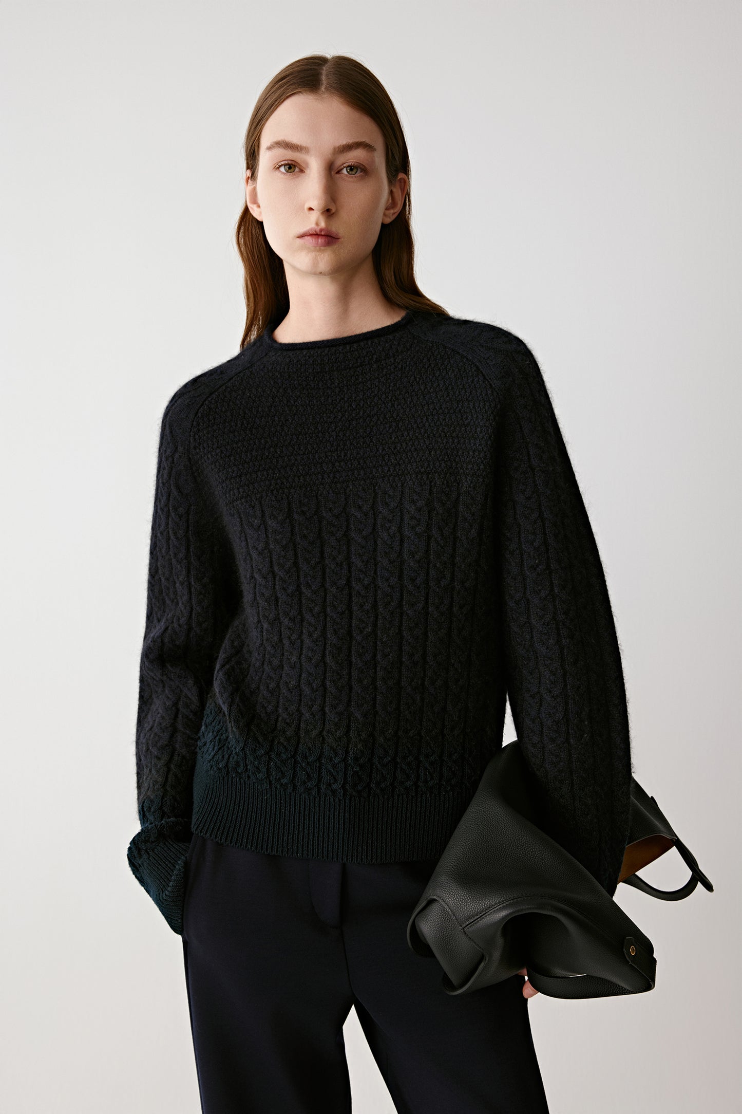 Front view of a model wearing a navy cable-knit cashmere jumper paired with dark trousers.
