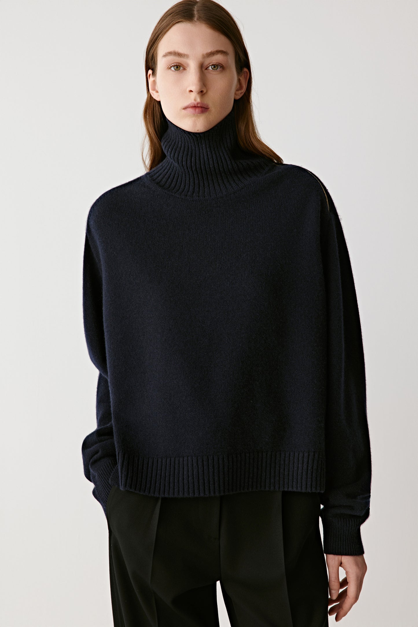 Portrait view emphasizing the ribbed funnel neck and shoulder zip detail.