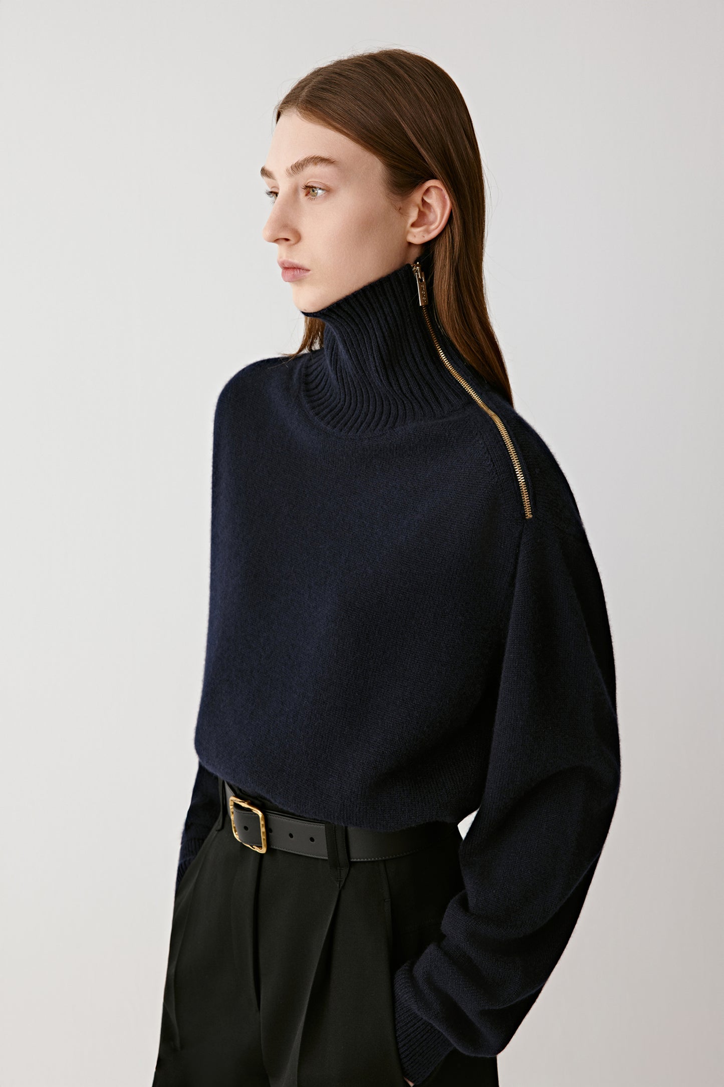 Full-length front view of the model wearing the navy blue cashmere jumper tucked into high-waisted trousers, showing its structured drape.