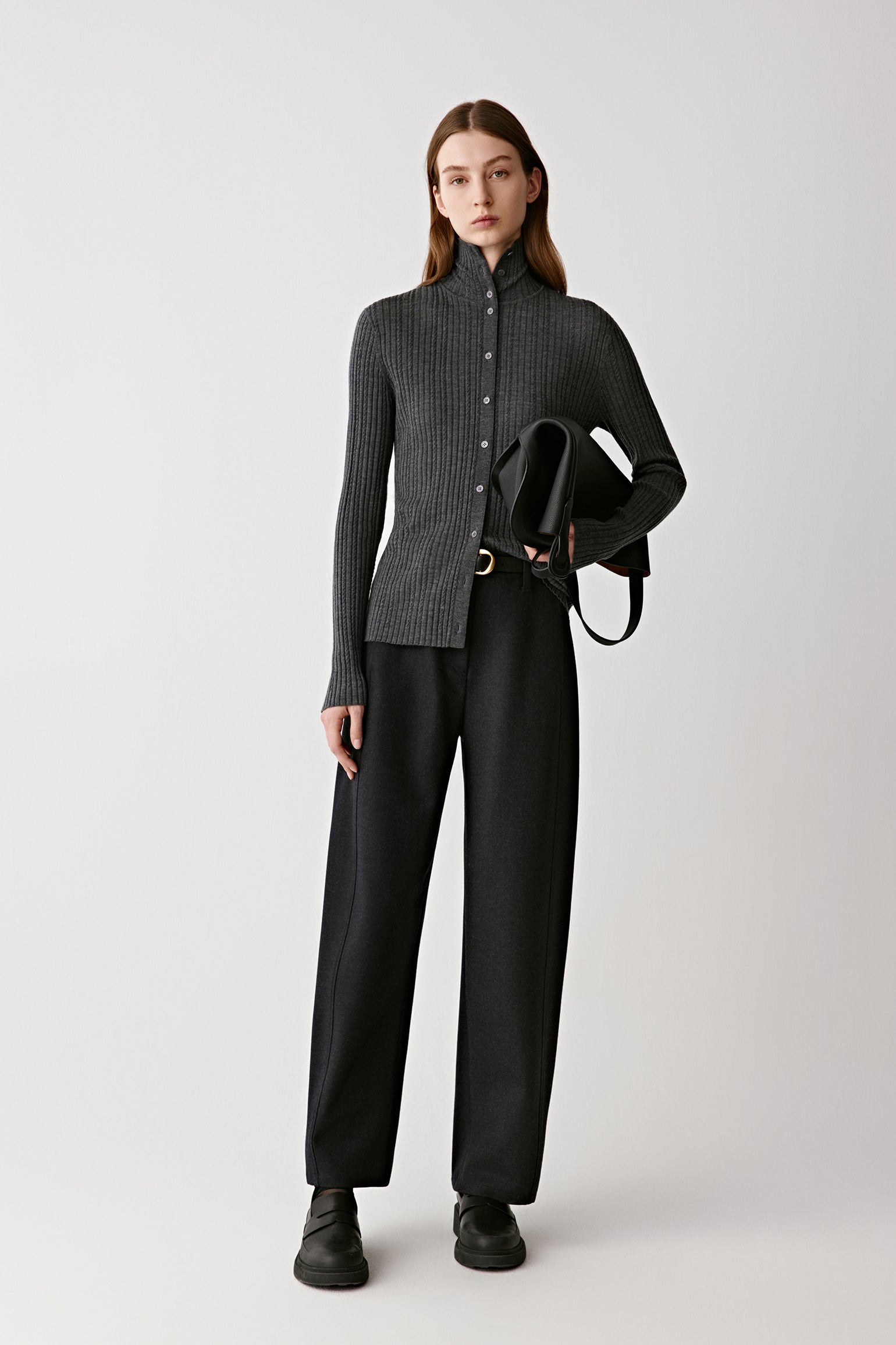 Front view of a woman wearing dark grey wool trousers with a high waist and clean straight leg.