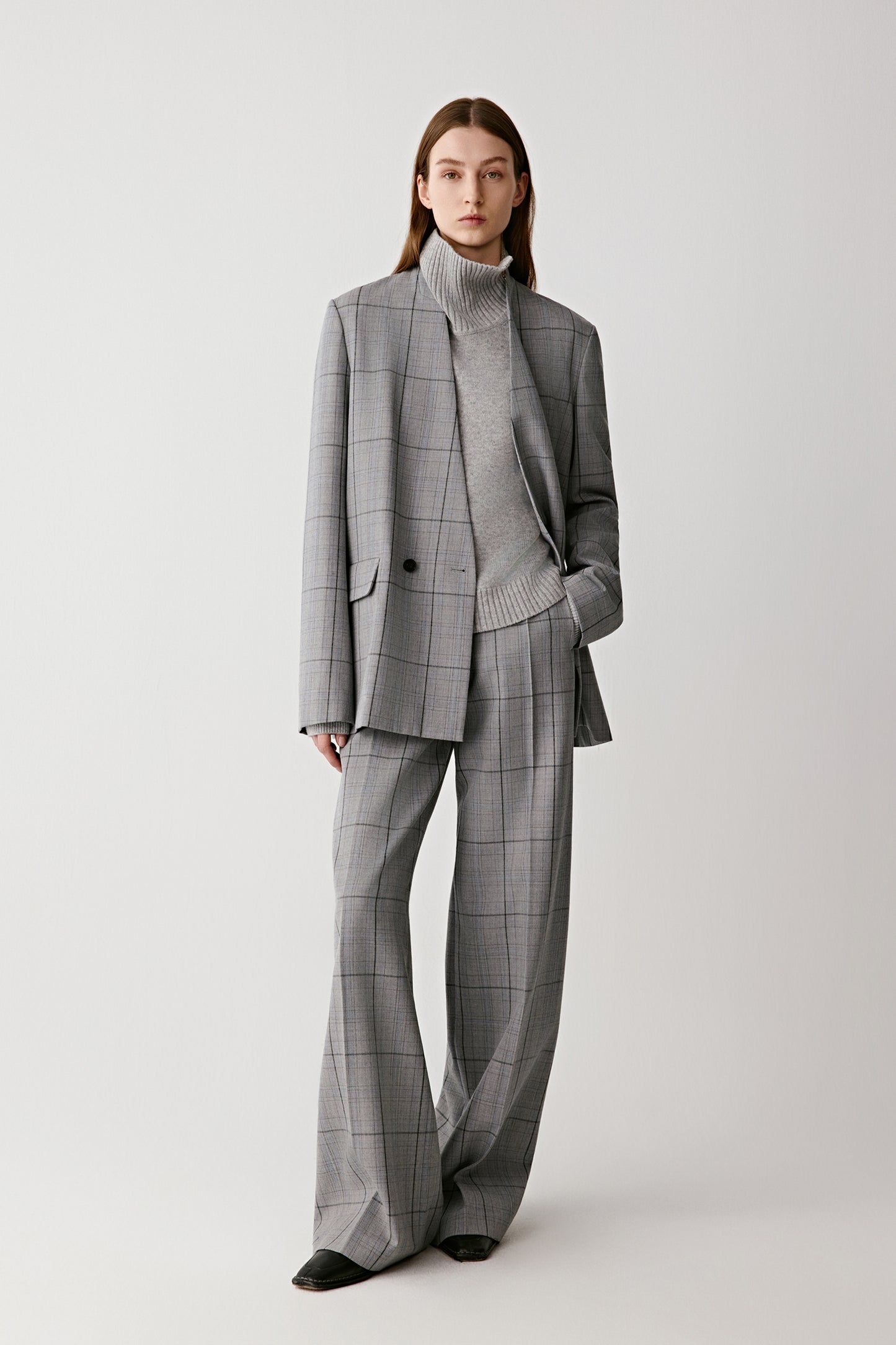 Person wearing a gray checkered suit on a white background