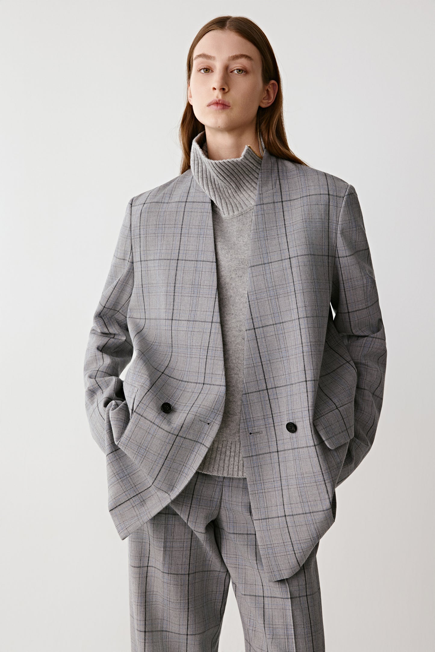 Person wearing a gray checkered blaser on a white background