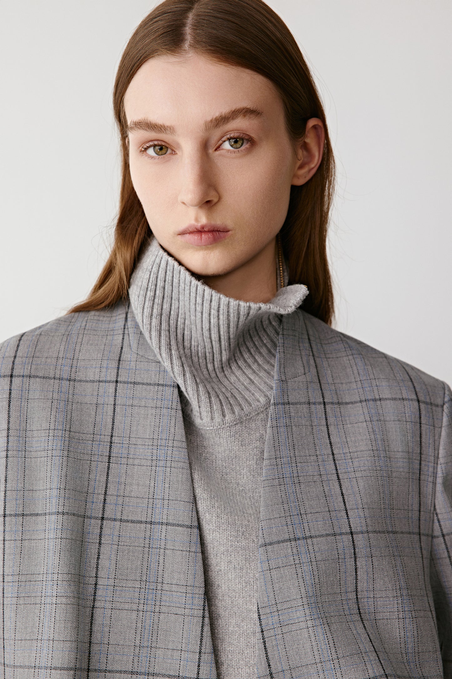 Person wearing a gray checkered blaser on a white background
