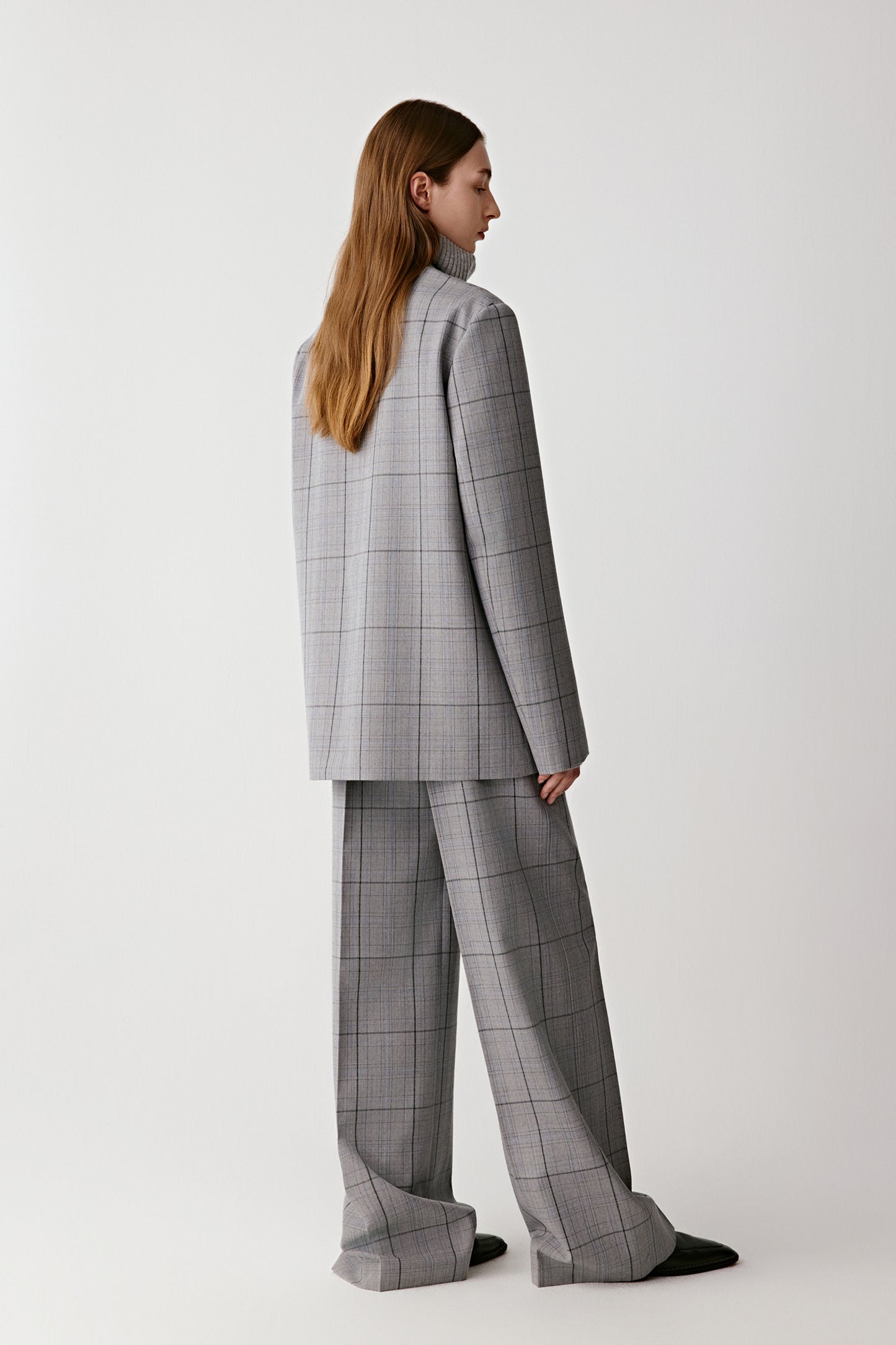 Person wearing a gray checkered suit on a white background