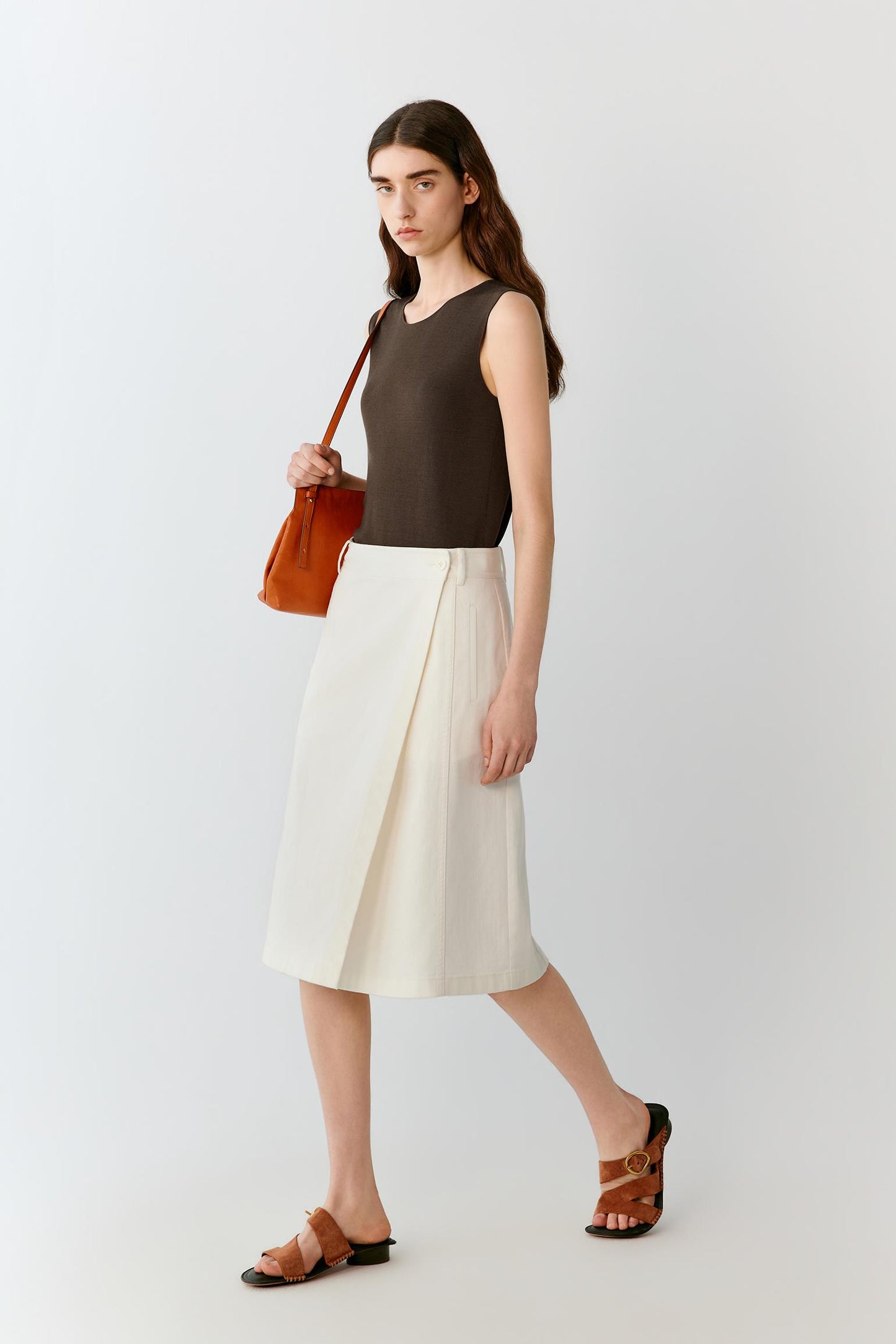 Three-quarter rear view showing the clean back construction, straight silhouette and fluid movement of the lightweight silk knit. The image emphasizes the balanced proportions and understated design of the garment.