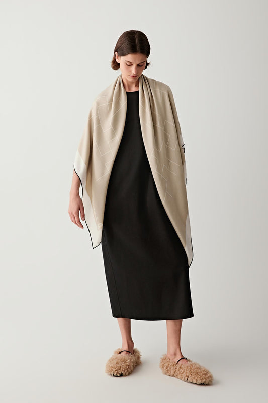 Full-length view of the model with the beige scarf worn loosely over a dark outfit, highlighting contrast, drape, and overall proportions.