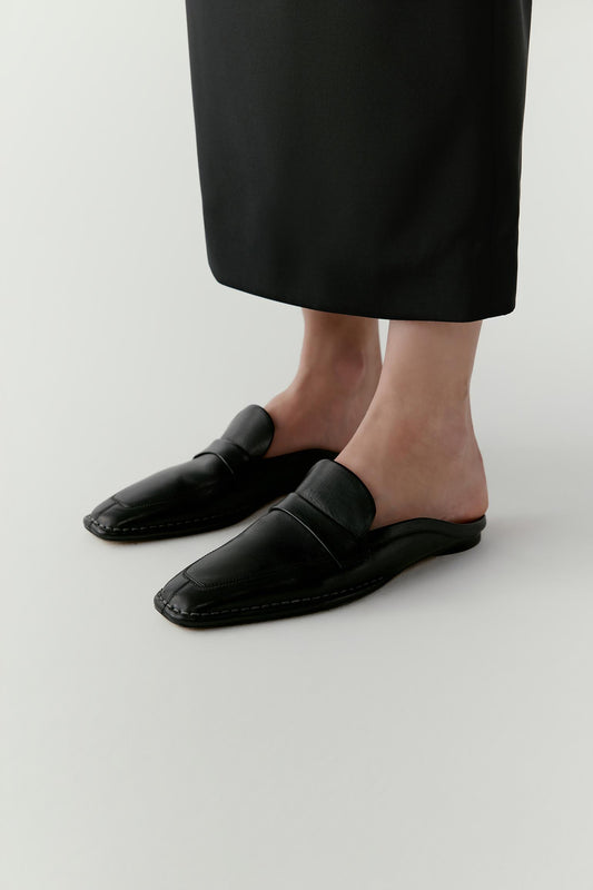 Three-quarter view showing the open heel and smooth calf leather surface, emphasizing the streamlined shape.