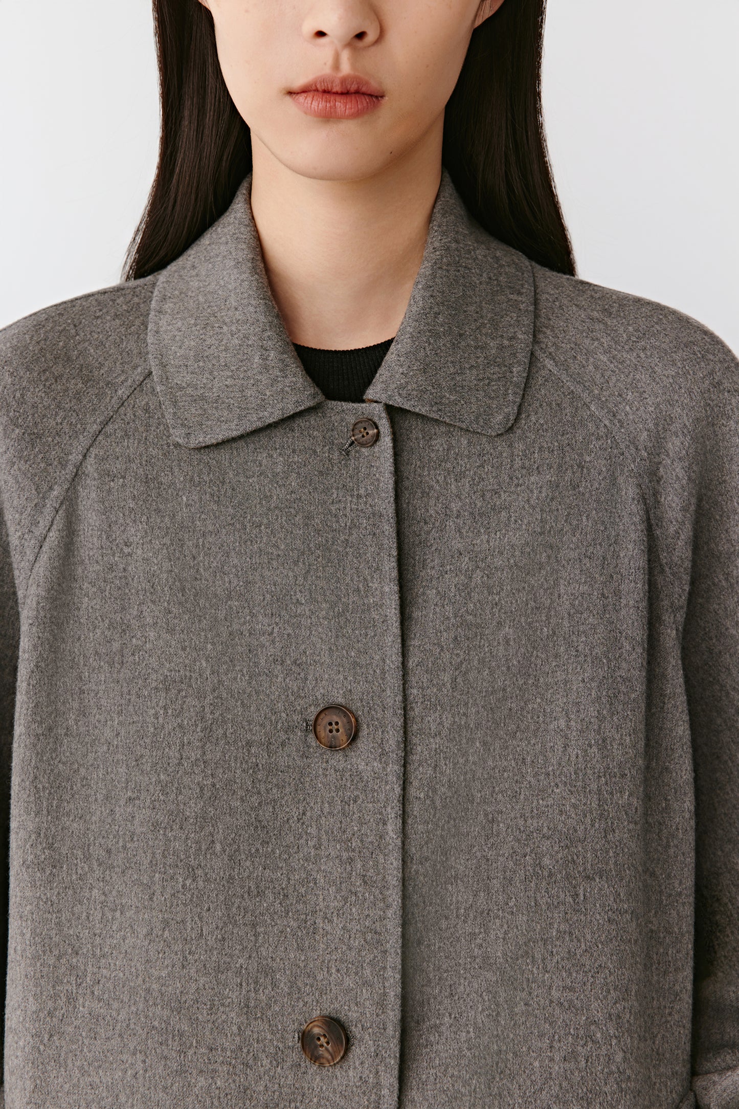 Focus on the front collar, buttoned placket, and fine tailoring that defines the pared-back design.