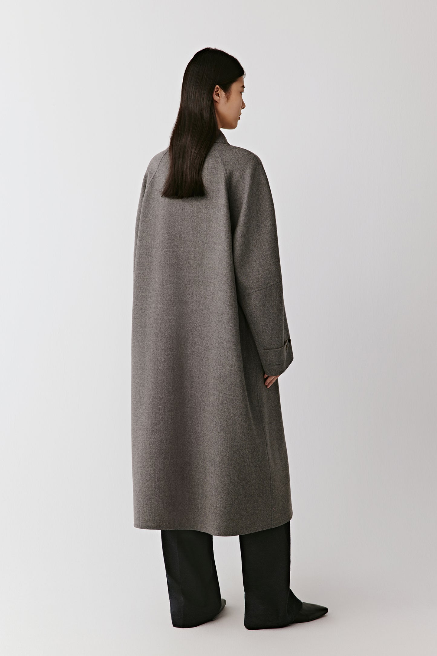The back of the coat emphasizing its straight construction and fluid movement.