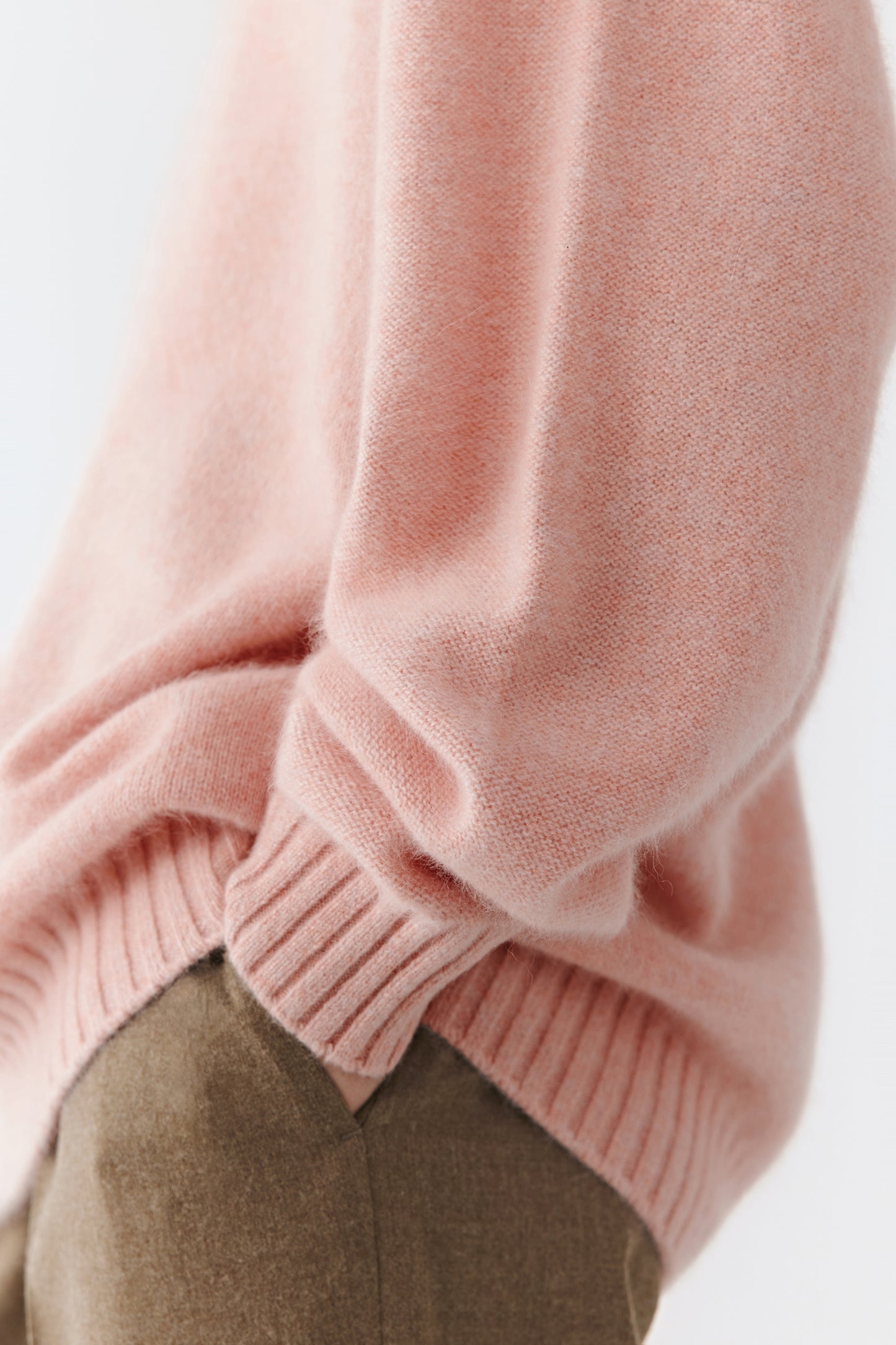 Close-up of the sleeve cuff and hem showing the fine ribbed knit and subtle pink hue.
