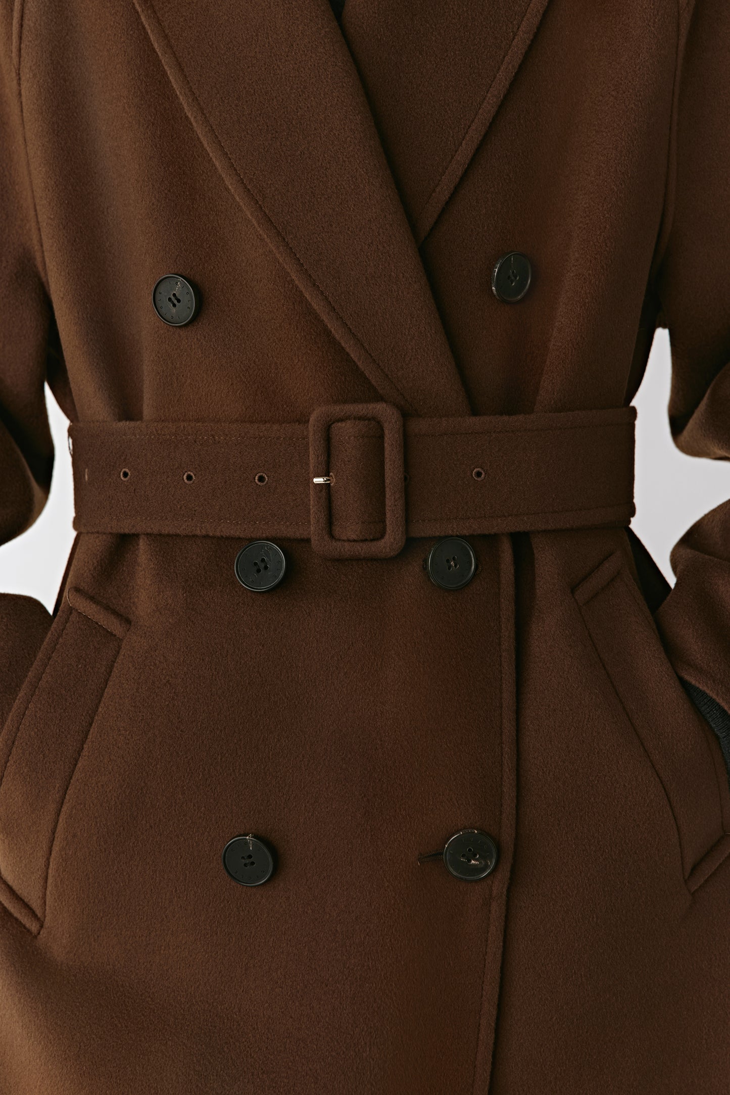 Close-up of the belt and cuff showing the buttoned tab and fine cashmere texture.