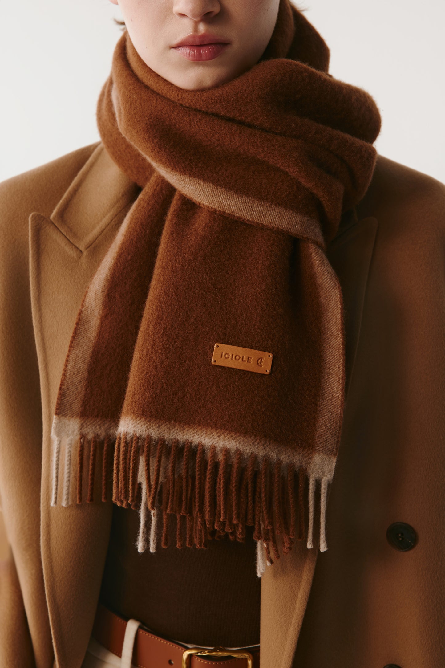 Detail view of a brown wool scarf with fringe on a light background