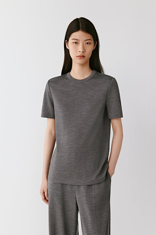A woman moves gracefully under soft light, wearing a dark heather grey T-shirt in brushed wool jersey.
The video opens with a full-length view, showing the fluid drape and relaxed fit.
As she turns, the camera shifts to mid-shot, highlighting the clean lines and natural softness of the wool.
Gentle close-ups reveal the fine texture of the brushed jersey and the subtle matte finish.
The sequence ends with a calm still, emphasizing the T-shirt’s effortless comfort and understated elegance.
