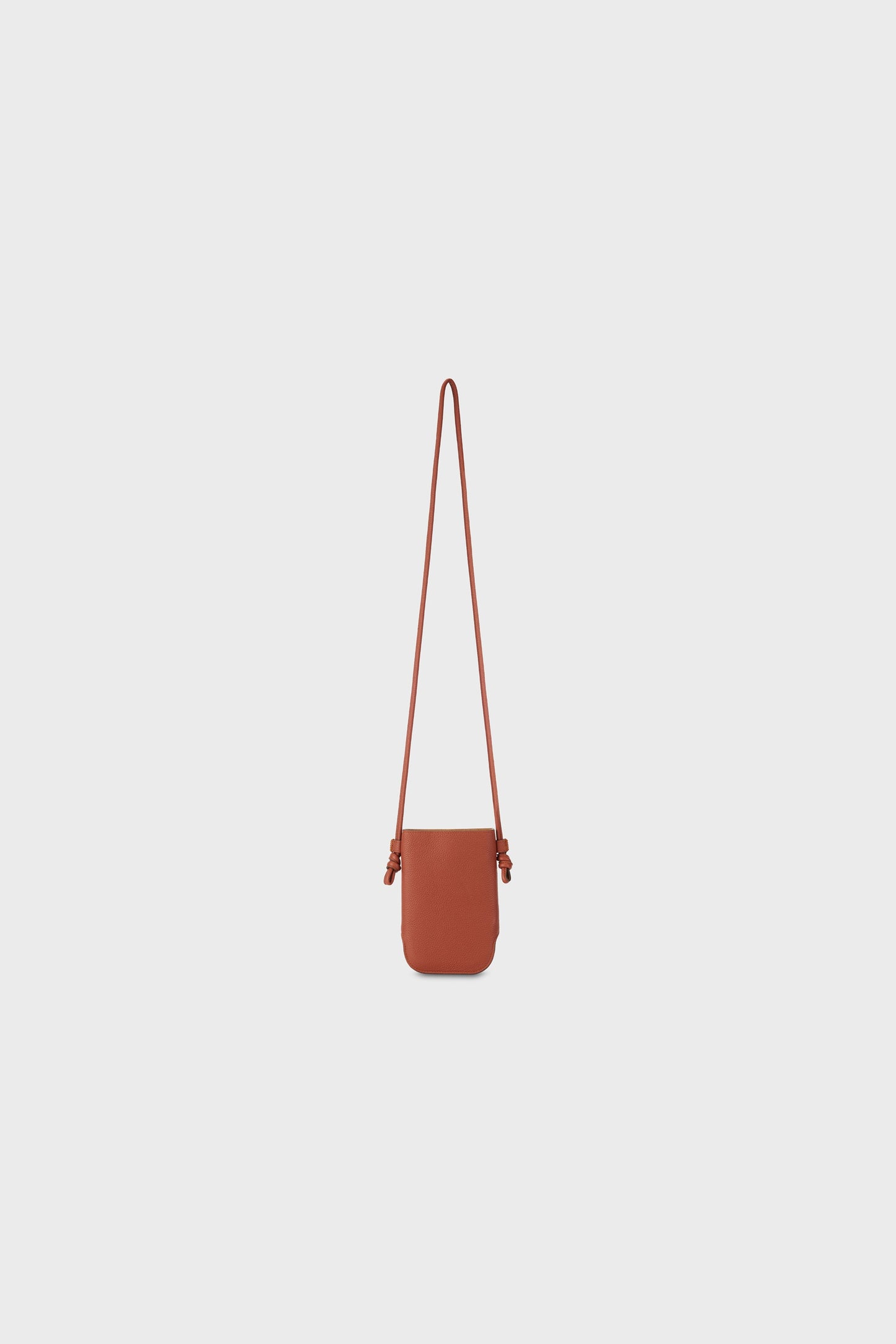 Front view of a brown leather shoulder bag with a long strap, photographed on a neutral background.