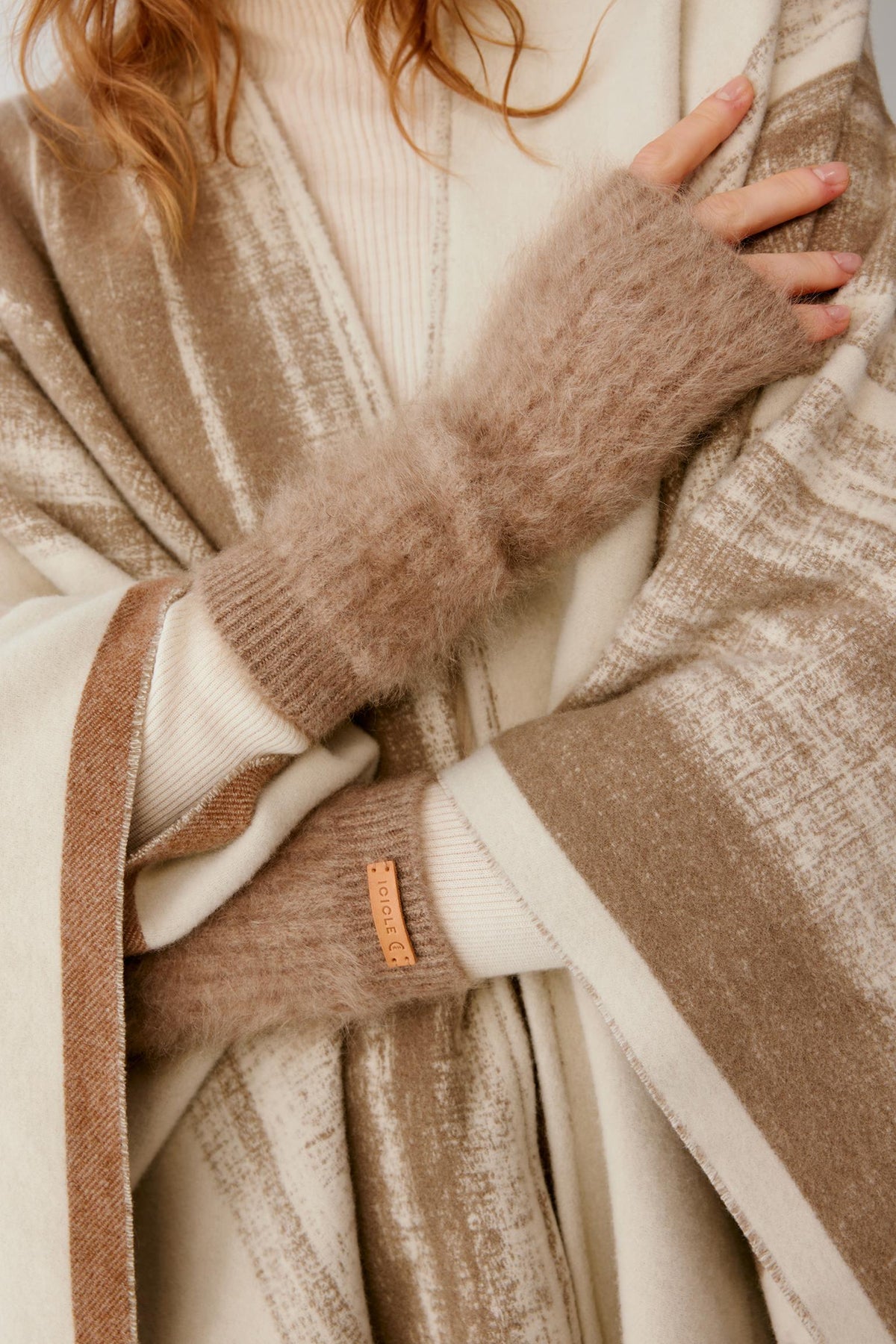 Close-up of natural taupe brushed cashmere fingerless gloves, showing the elongated ribbed construction and open fingers.