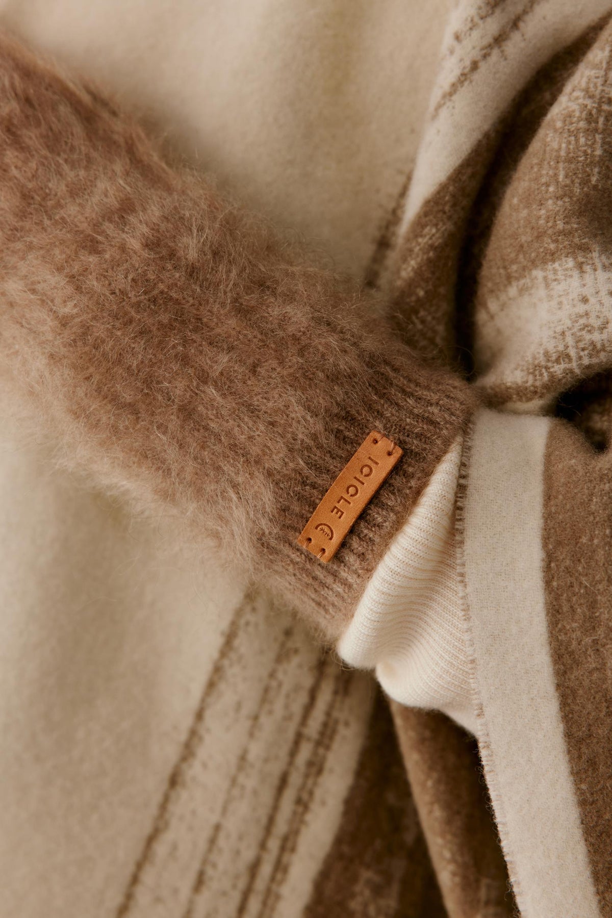 Side detail of a woman wearing natural taupe brushed cashmere fingerless gloves, showing the open-finger construction and brushed texture.