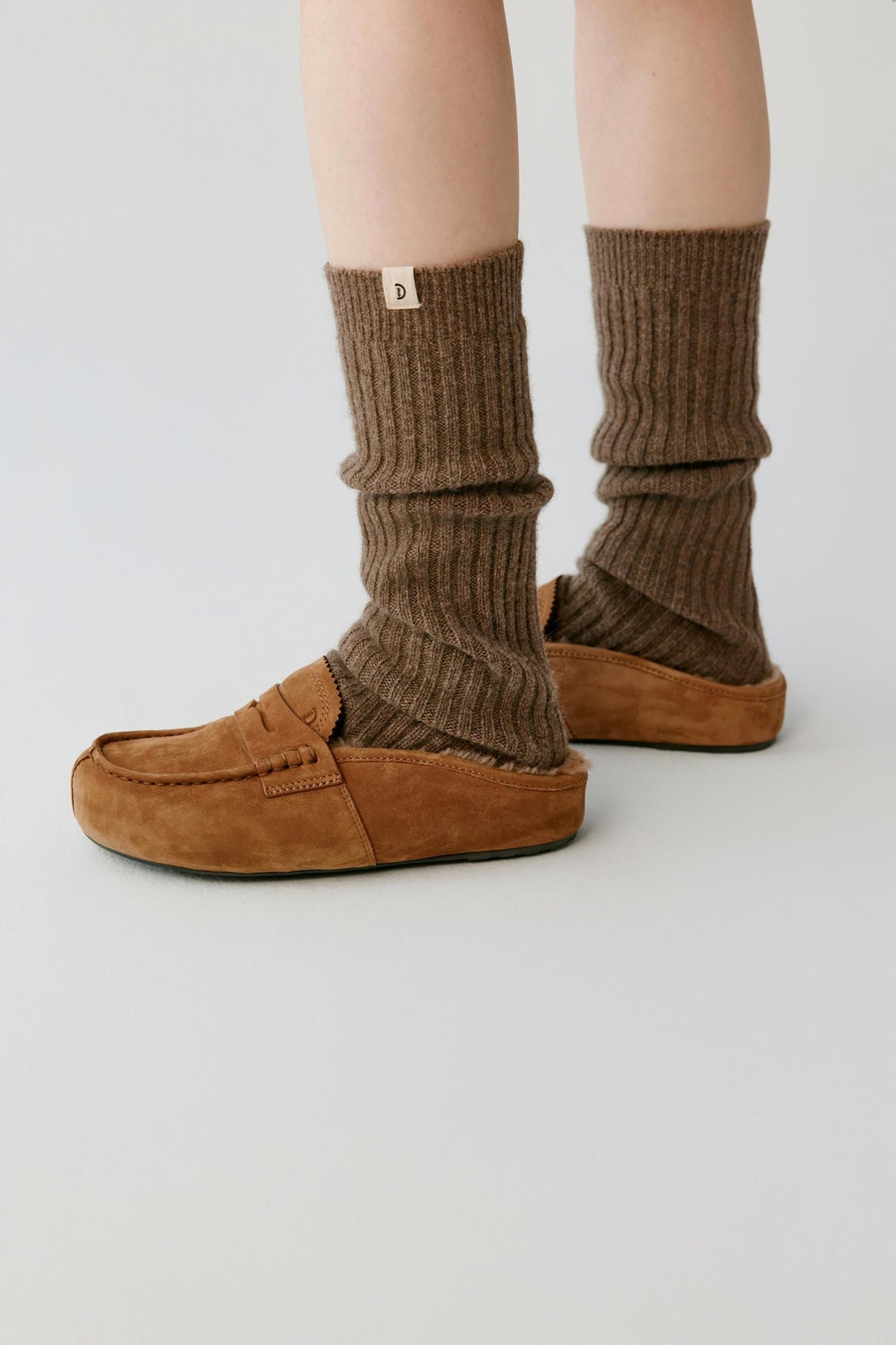 Side view highlighting the open-back construction, low profile and chestnut brown nubuck surface of the mules.