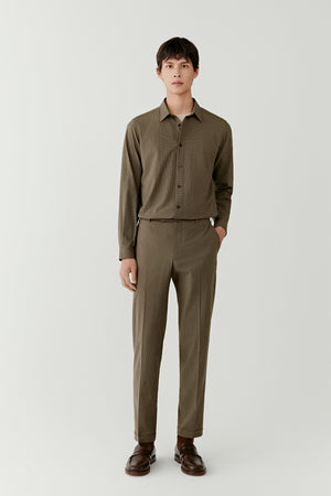 Man wearing khaki check trousers in a silk and wool blend with a straight tailored fit, styled with a matching khaki shirt, full-length front view.