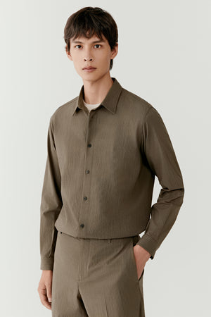 Man wearing a khaki silk-and-wool check shirt with relaxed straight fit, styled with matching khaki trousers, front three-quarter view.