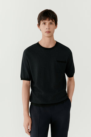 Man wearing a dark green wool knit T-shirt with straight relaxed fit, front portrait view.