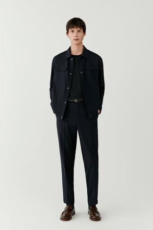 Man wearing a dark navy and charcoal checked wool and silk jacket with straight tailored cut, styled with matching trousers, full-length front view.