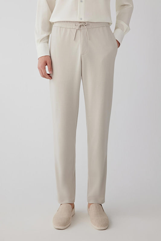 Front view from waist to ankle highlighting the straight-leg shape, smooth fabric surface and fluid drape of the wool jersey.