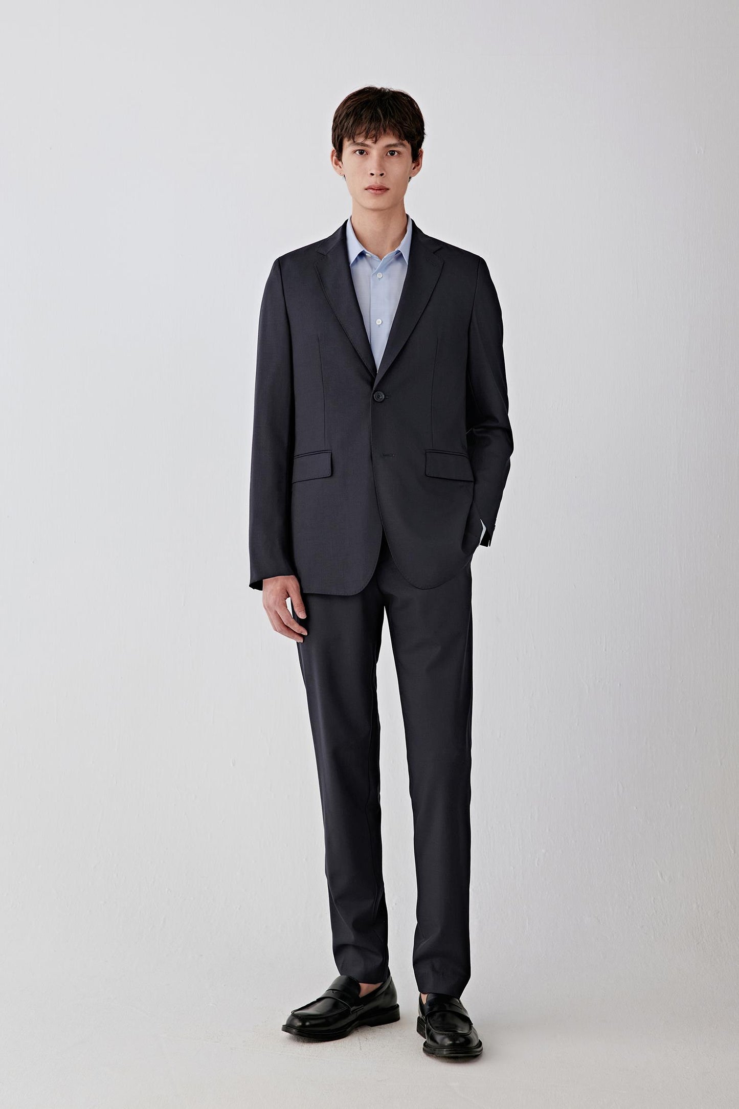 Full-length front view highlighting the single-breasted closure, straight silhouette and even fall from shoulder to hem, creating a sharp, elongated line.