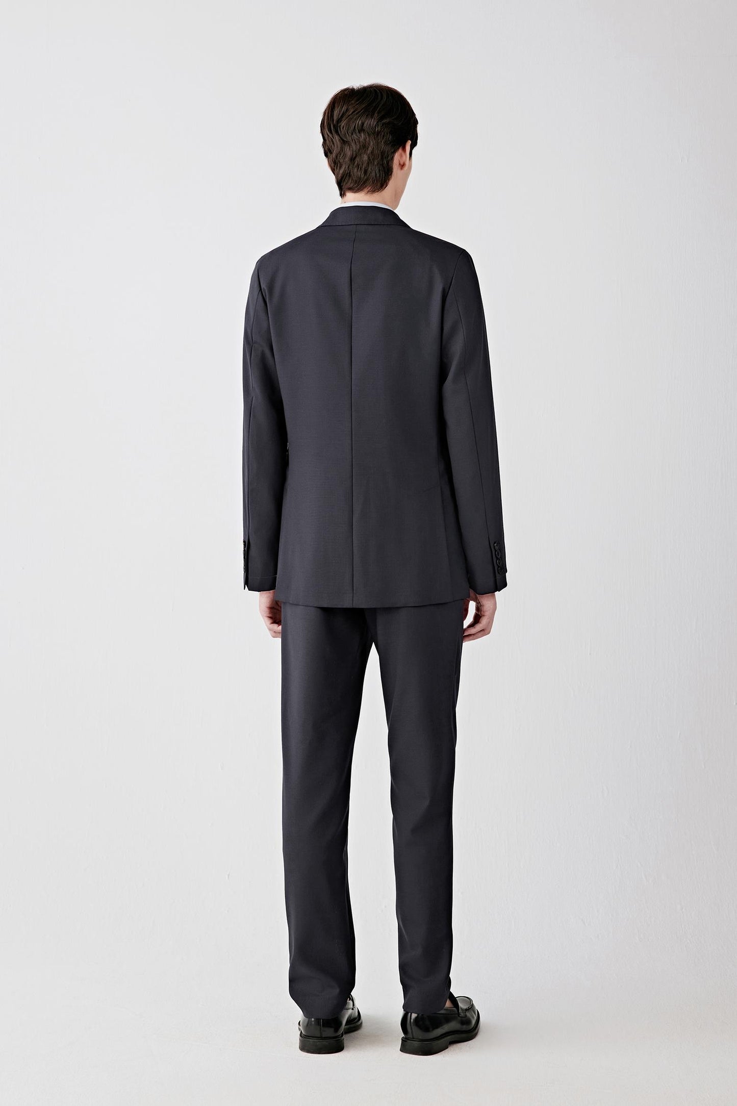 Back view showing the clean back panel, straight cut and structured drape through the shoulders and upper back.