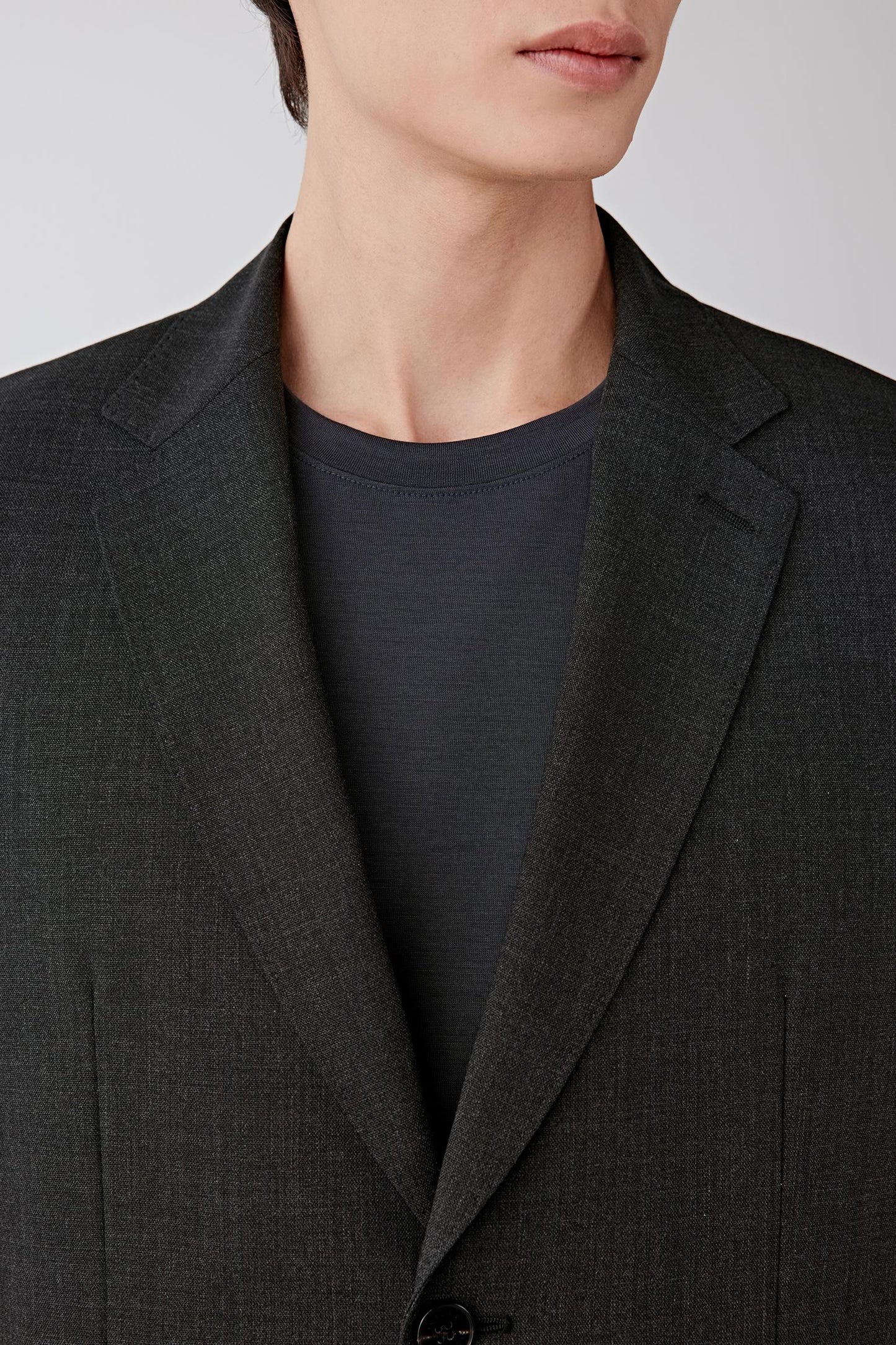 Close-up of the lapel and chest area, revealing the fine twist wool texture, subtle matte finish and precise tailoring.