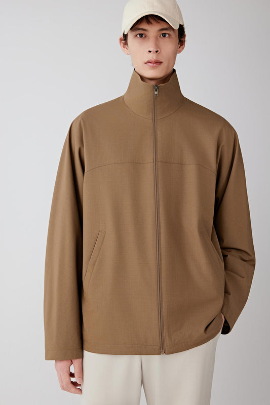 Man wearing a brown jacket and beige cap on a white background