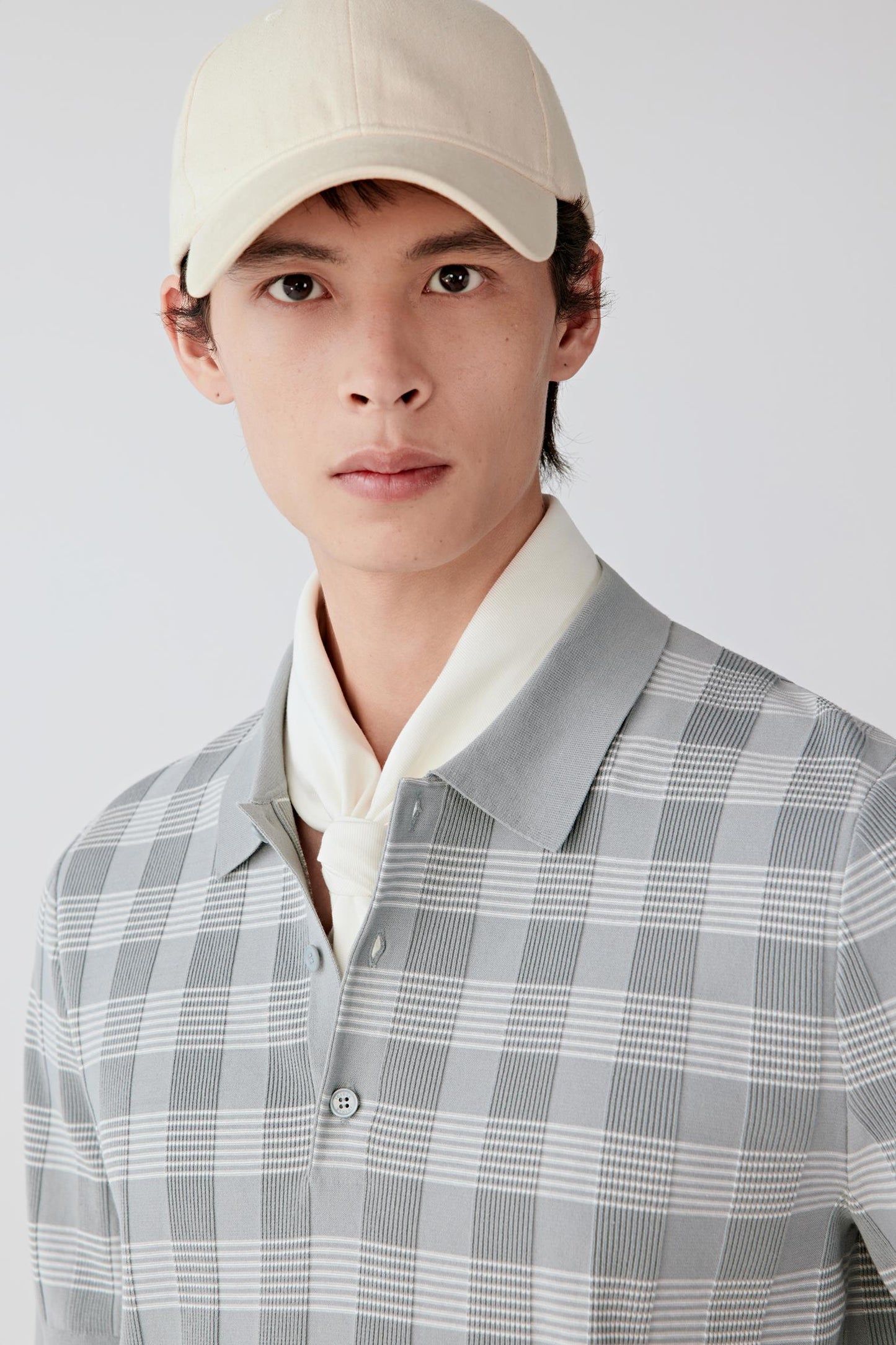 Close-up of the upper body showing the polo-style collar, short button placket with visible buttons and the fine checked knit pattern integrated into the fabric.
