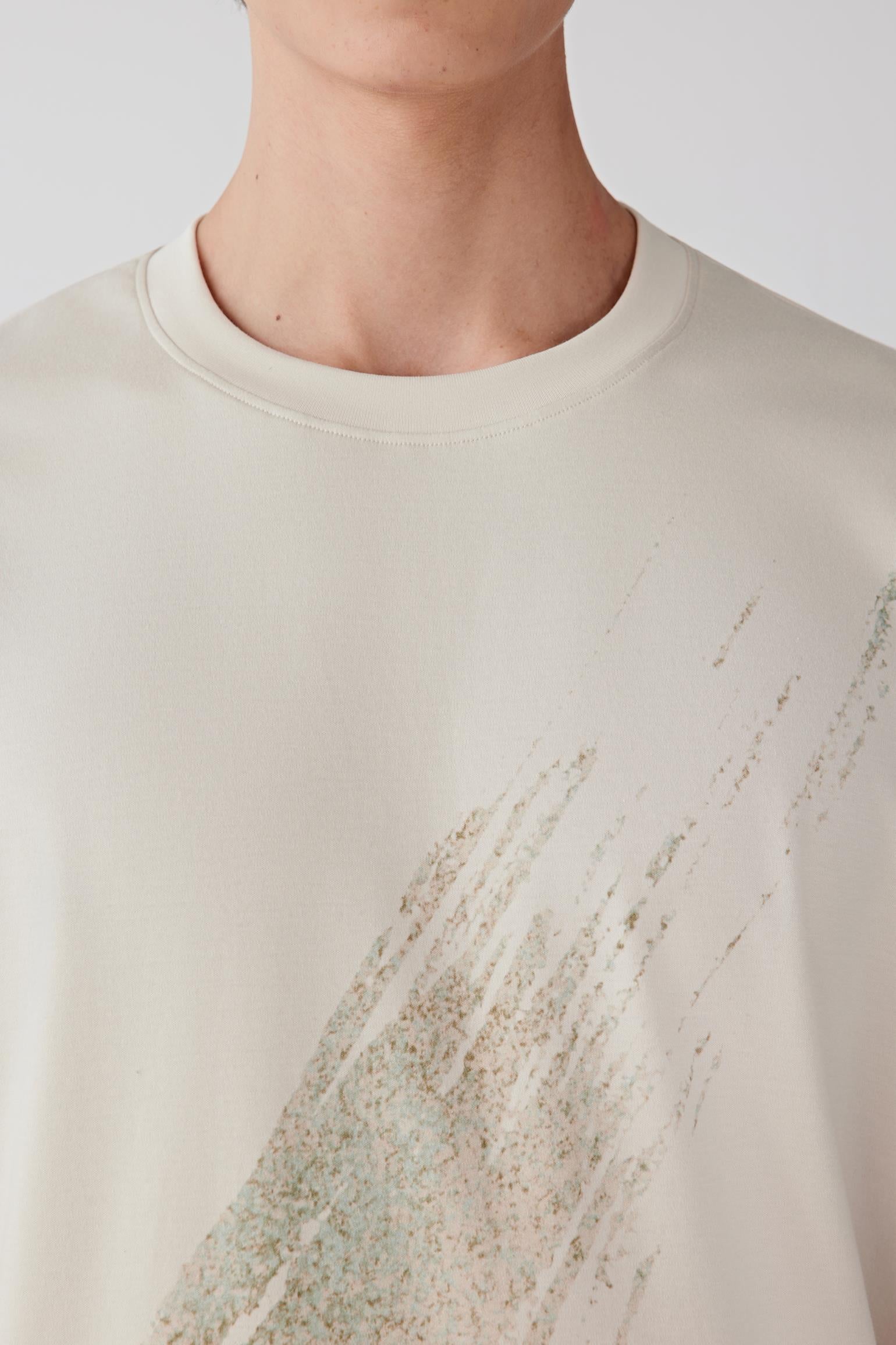 Close-up of the chest area showing the round neckline, fine ribbed collar and subtle textured graphic integrated into the fabric.