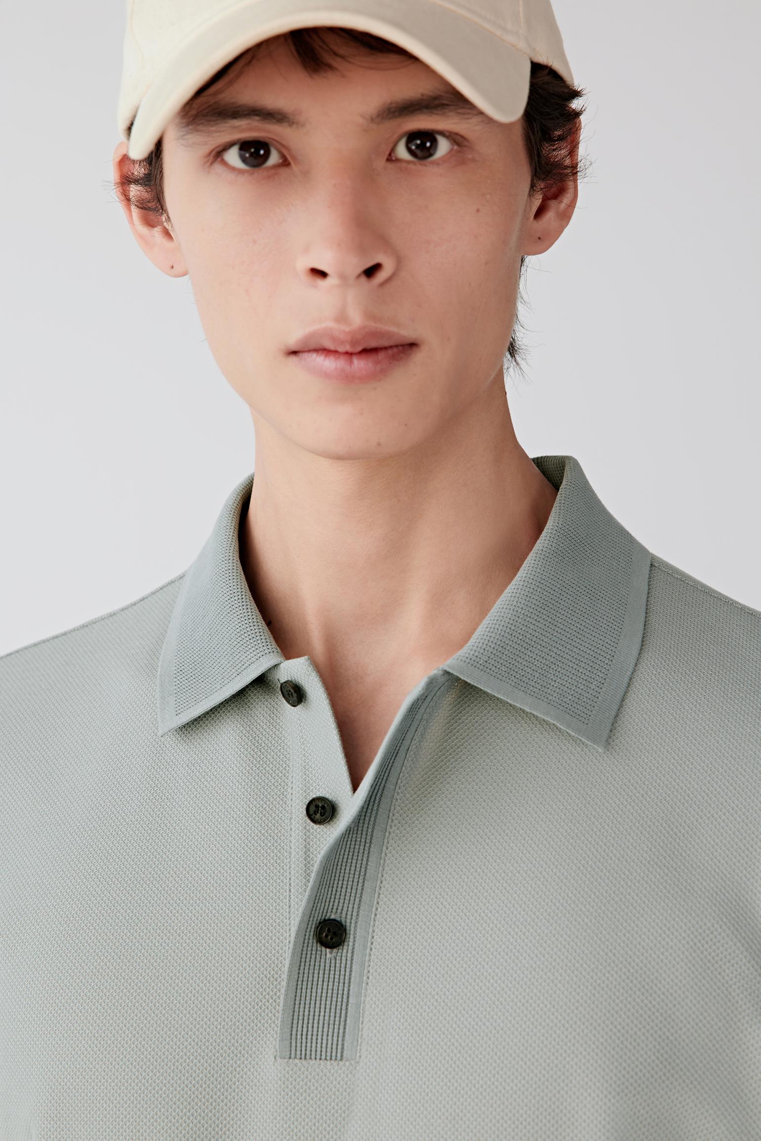Close-up of the upper body showing the classic collar, short button placket and fine knit texture.