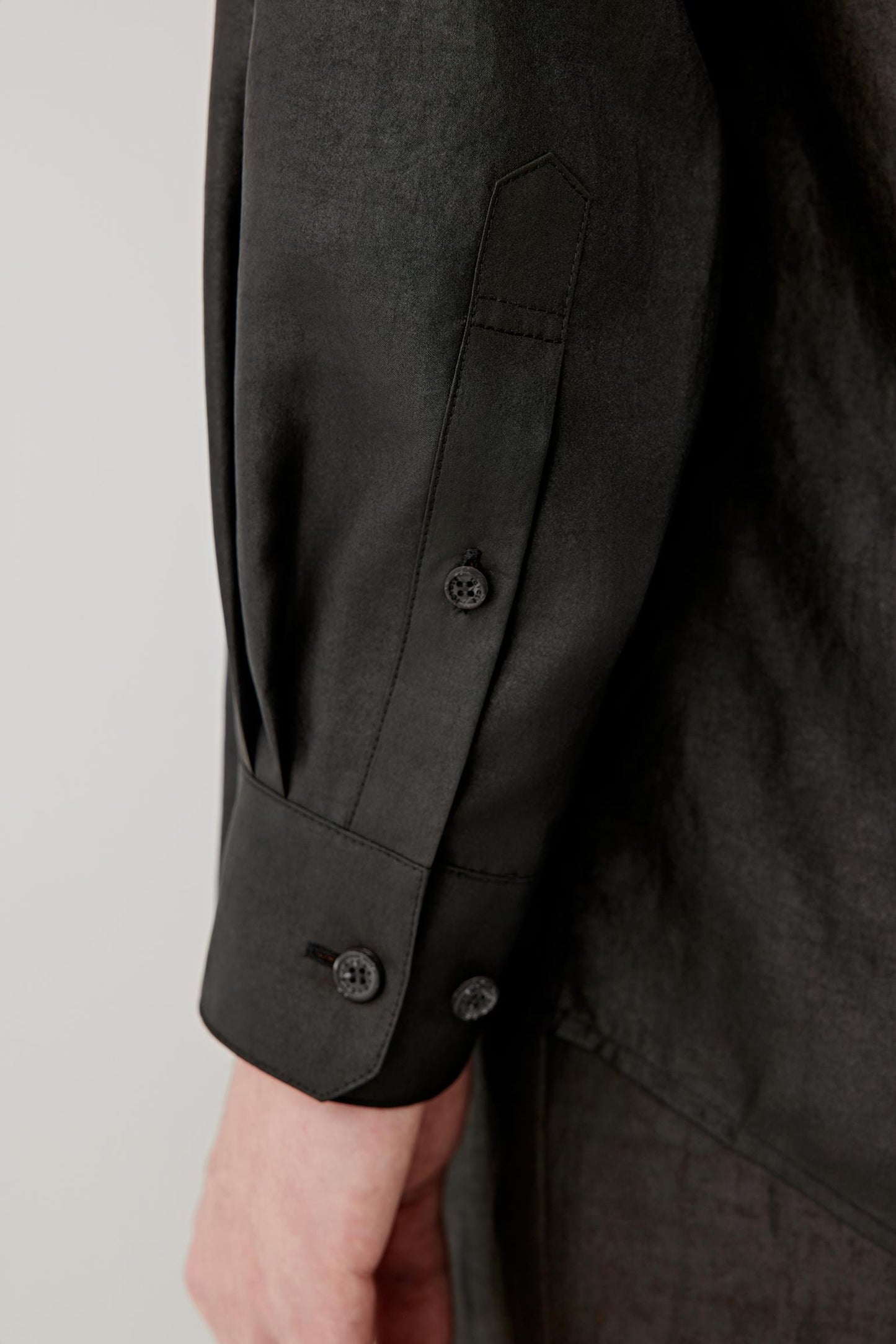 Detail of the cuff and sleeve, highlighting the buttoned cuff, soft fabric hand and slightly matte, textured finish.