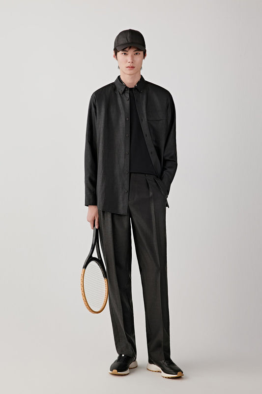 Man wearing deep black Gambiered Canton gauze silk trousers with a straight, relaxed fit, paired with a matching jacket and light inner layer; full-length front view showing the fluid drape and slightly matte, textured surface.