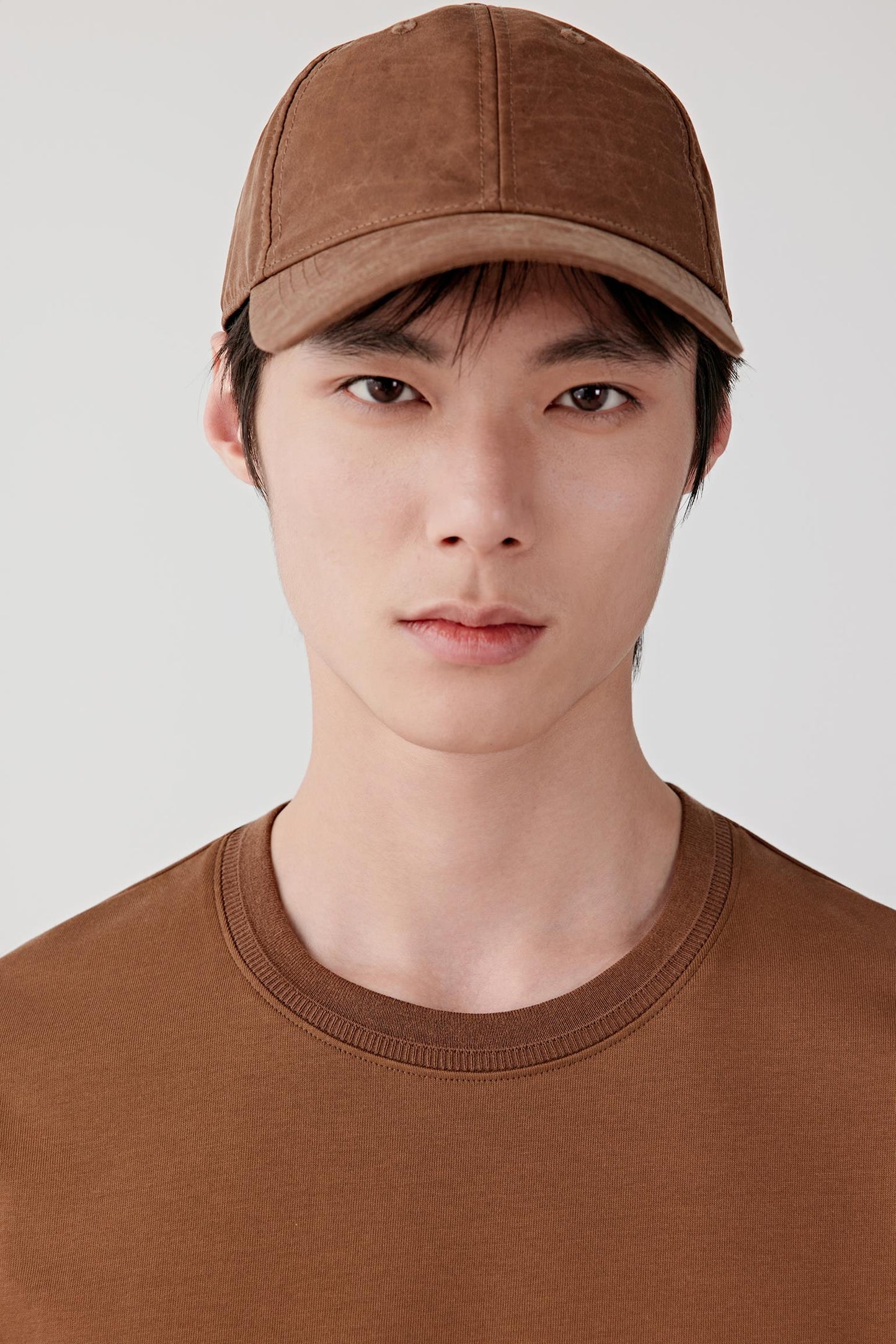 Close-up of the upper body showing the round neckline with fine ribbed collar and uniform cotton surface.