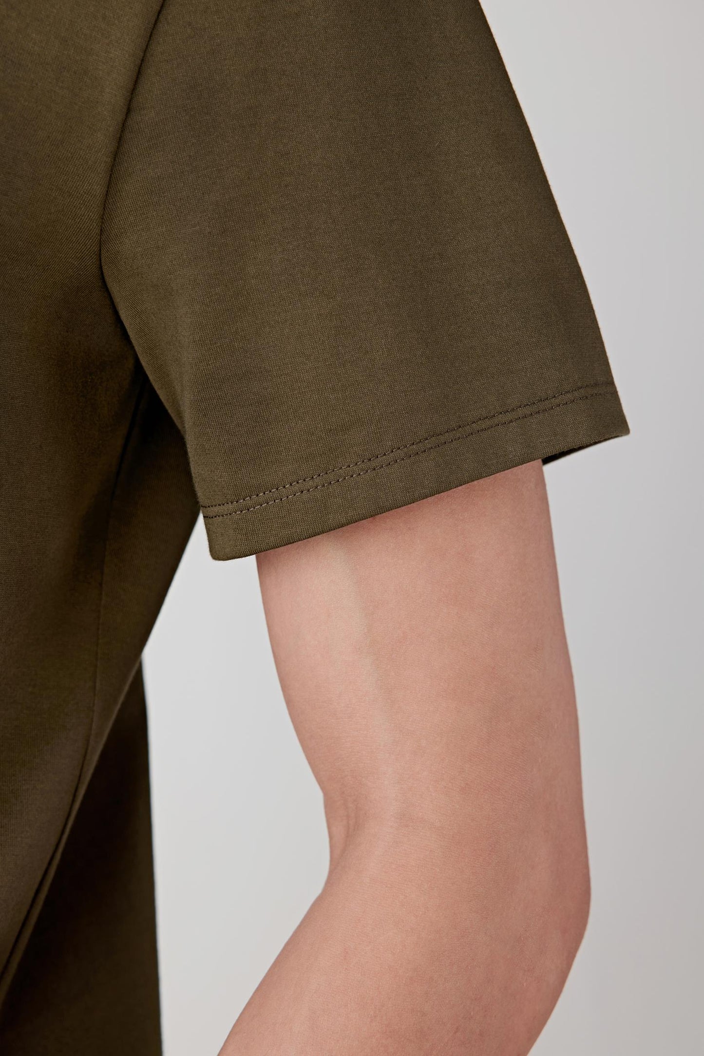 Close-up of the sleeve and side body, highlighting the short sleeve cut, clean finishing and the breathable, lightweight cotton jersey with a smooth hand feel