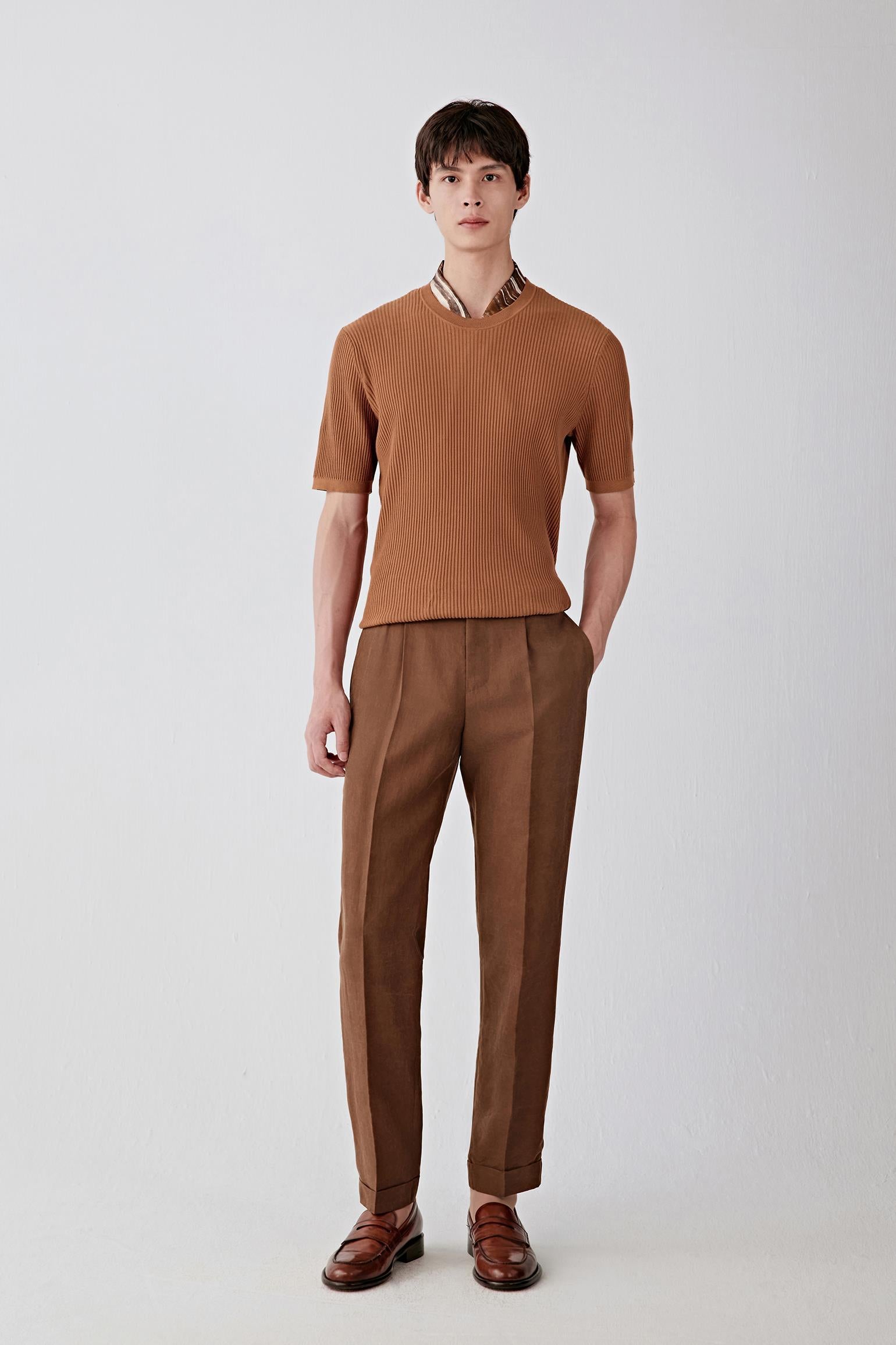 Full-length front view of a man standing facing forward wearing deep brown Gambiered Canton gauze trousers paired with a matching top, highlighting the straight, relaxed silhouette, clean leg line and structured yet breathable fabric, with a matte surface showing subtle tonal depth from the natural dyeing process