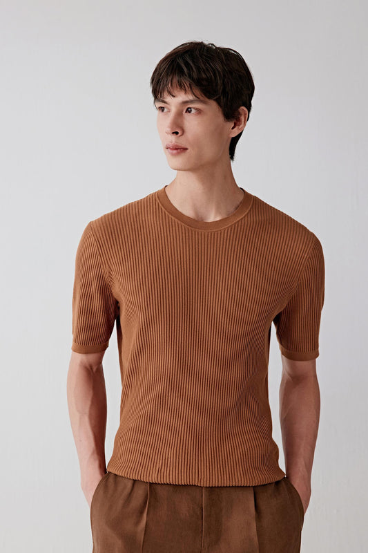 Three-quarter front view of a man wearing a brown fine-spun cotton pullover, highlighting the close-to-body fit, short sleeves and fine ribbed construction, with a smooth, matte surface and a warm brown tone showing slight tonal variation across the knit