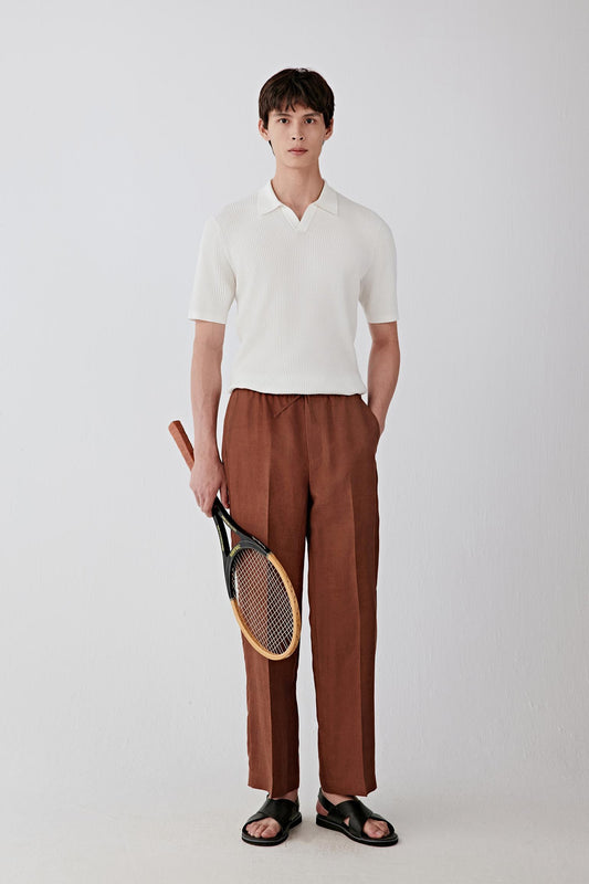 Full-length front view of a man standing facing forward wearing an ivory fine spinning cotton pullover, paired with brown trousers, highlighting the straight silhouette, lightweight knit structure and clean, balanced proportions