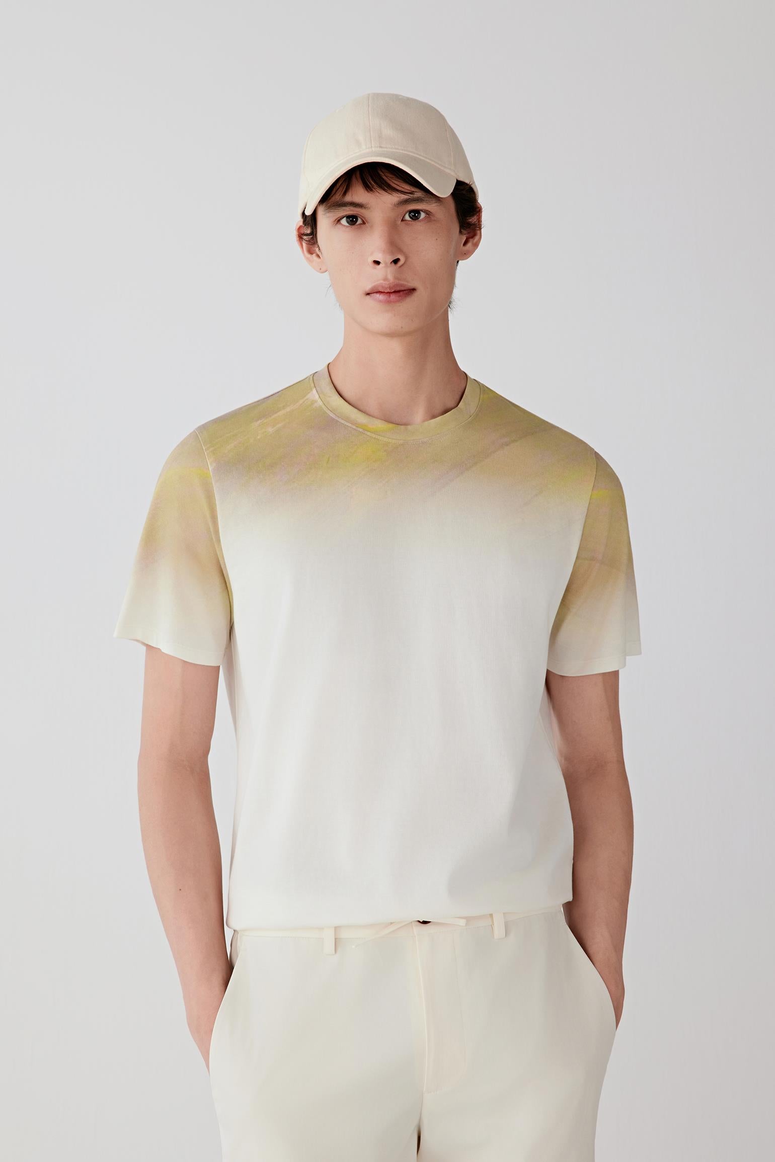 Front view of a man wearing a short-sleeved T-shirt in cotton jersey, presented in a white base shade with yellow and beige tonal transitions. The smooth jersey surface reveals a soft hand and lightweight structure.