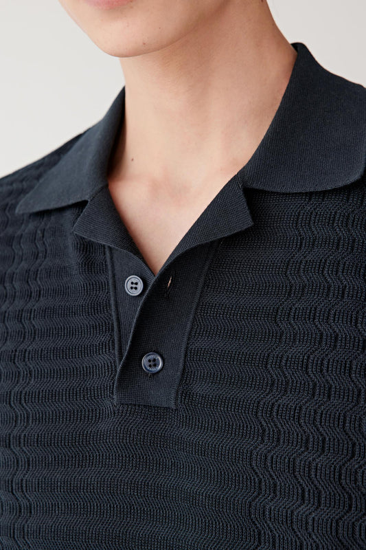 Close-up front view showing the polo collar and short sleeve construction. The lightweight knit maintains a clean and relaxed silhouette with subtle structure.