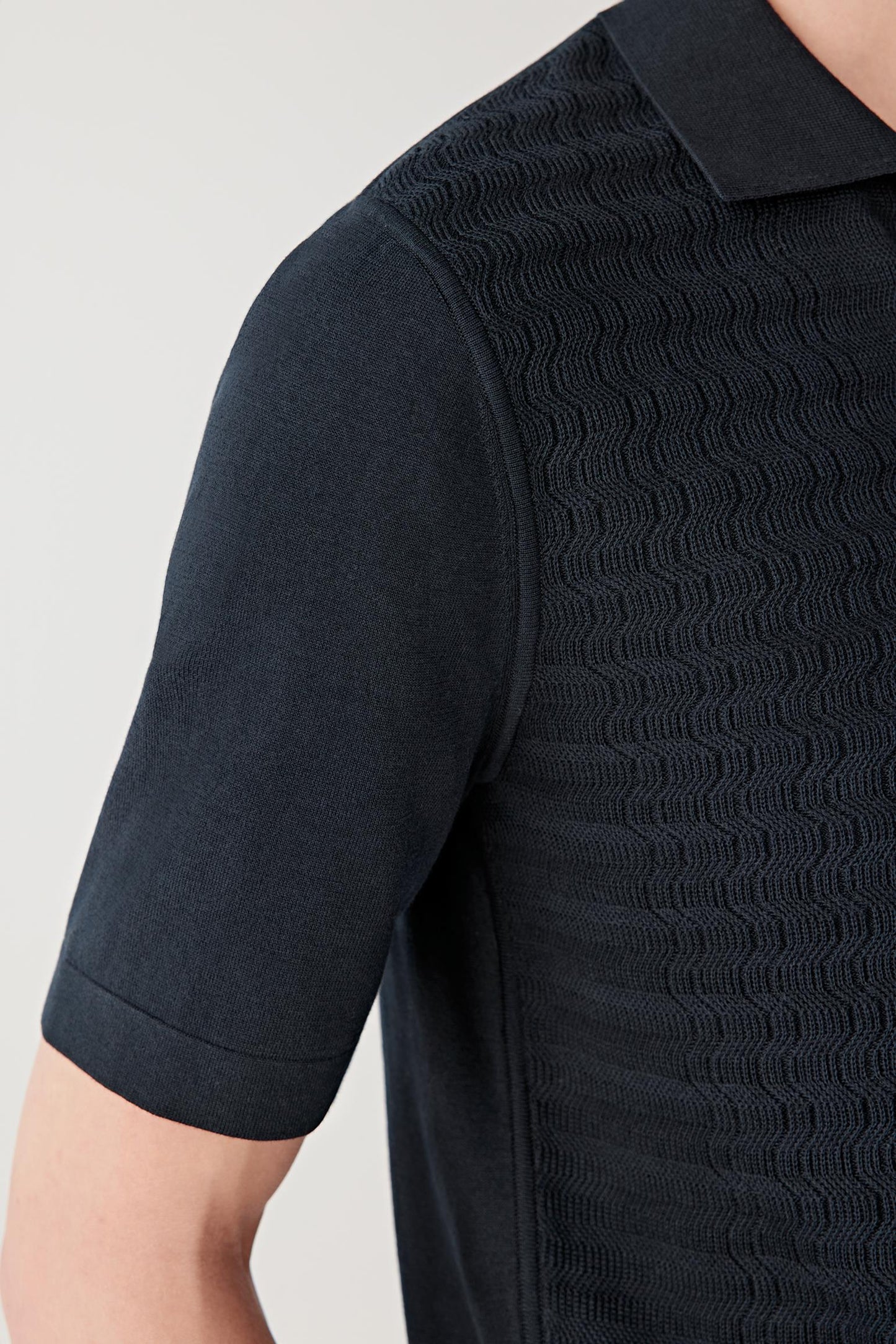 Close-up of the sleeve and fabric surface showing the lightweight knit structure, even stitch definition and breathable quality of the fine-spun cotton yarn.